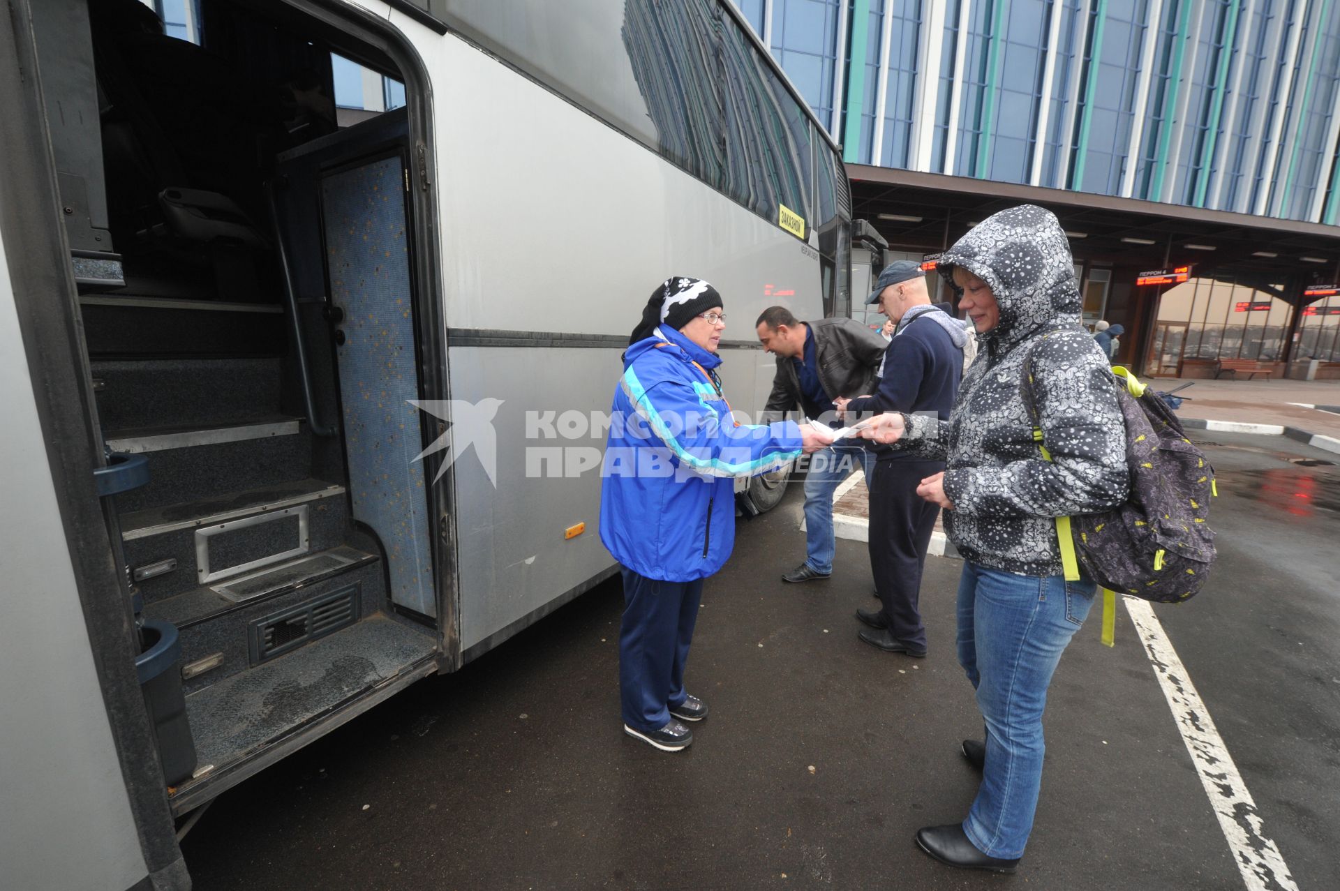 Москва.  Кондуктор проверяет билет у пассажира перед отправлением автобуса у здания международного автовокзала `Южные ворота` в Люблино.
