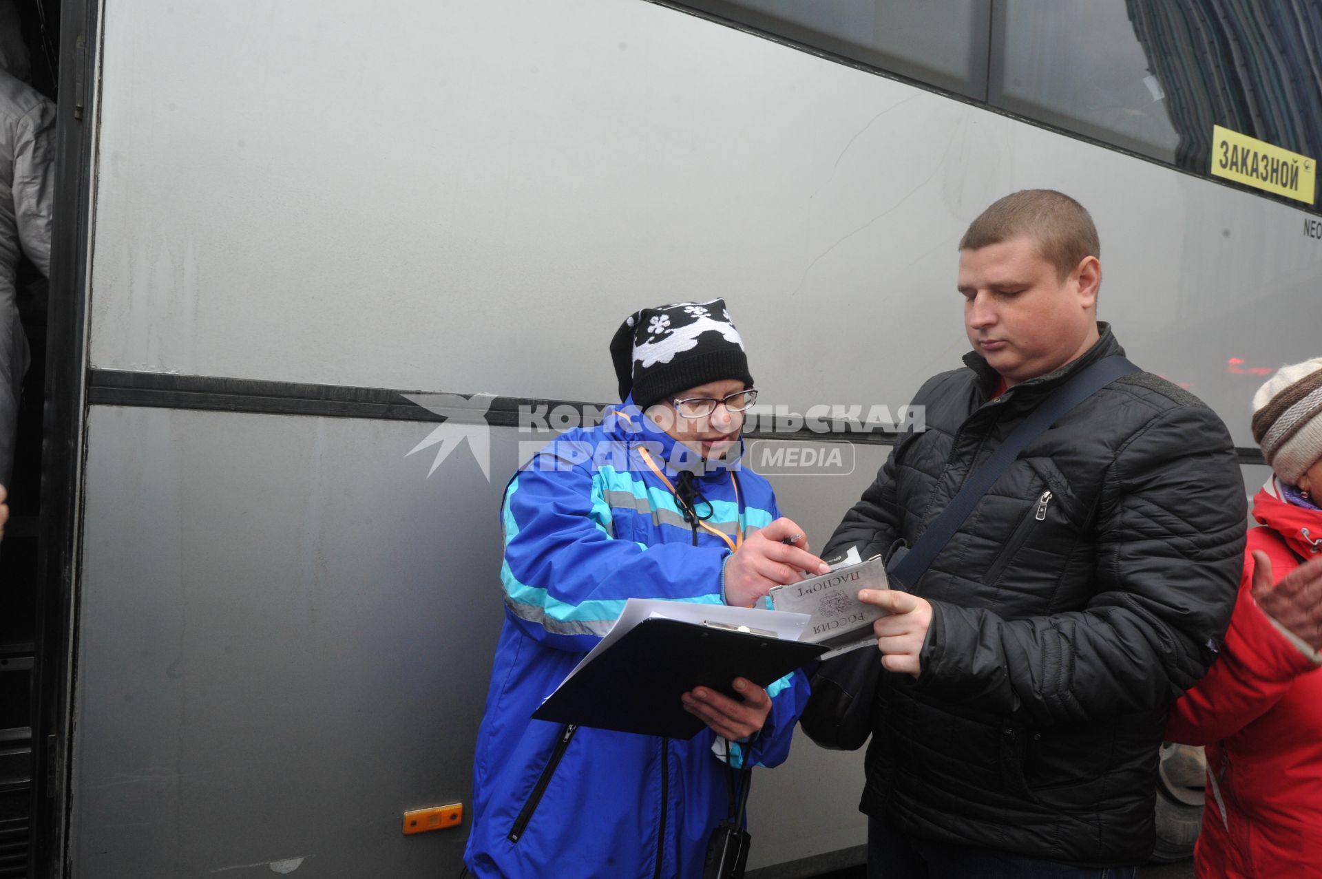 Москва.  Кондуктор проверяет билет у пассажира перед отправлением автобуса у здания международного автовокзала `Южные ворота` в Люблино.