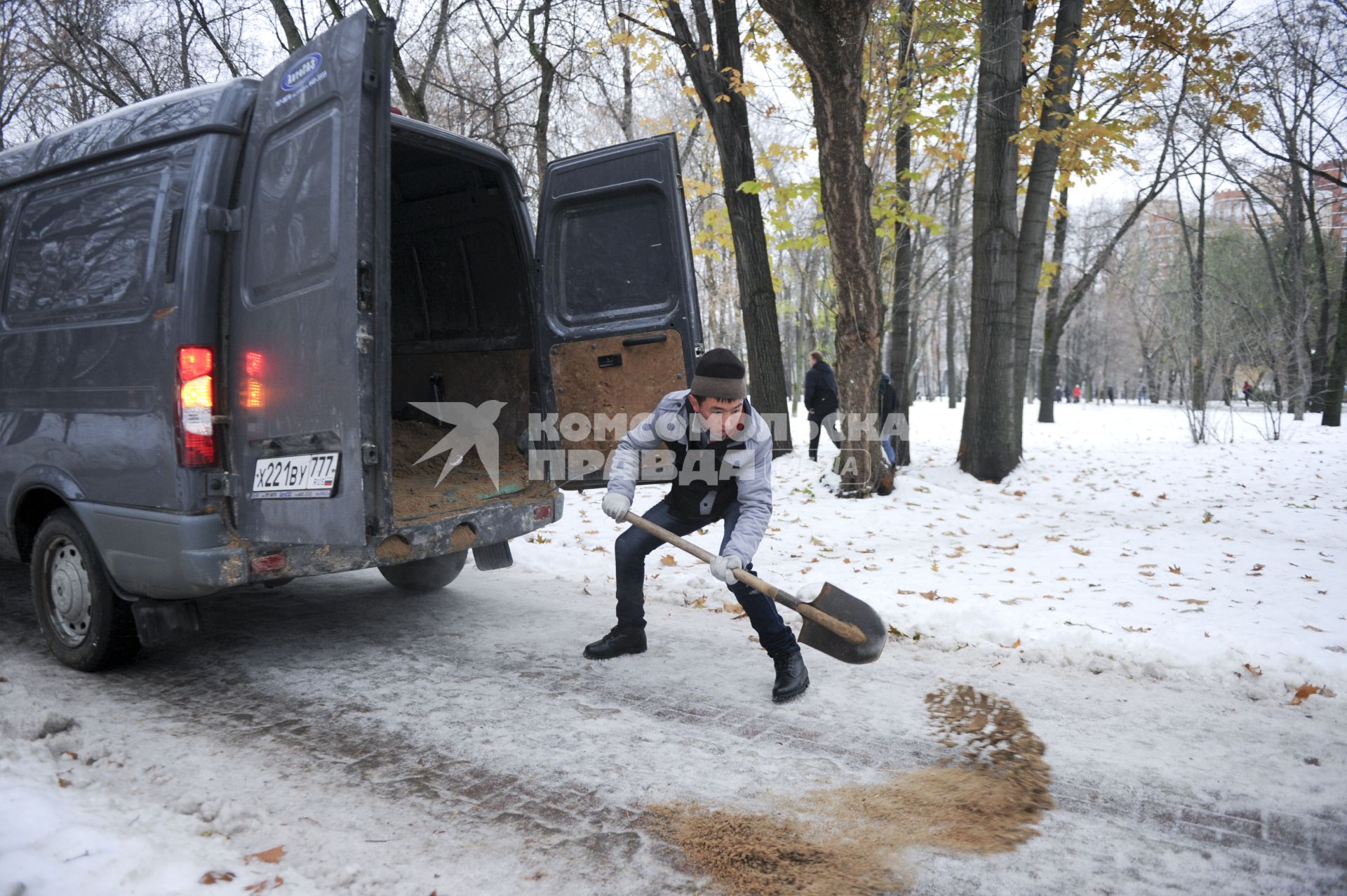 Москва. Дворник посыпает дорожки песком.