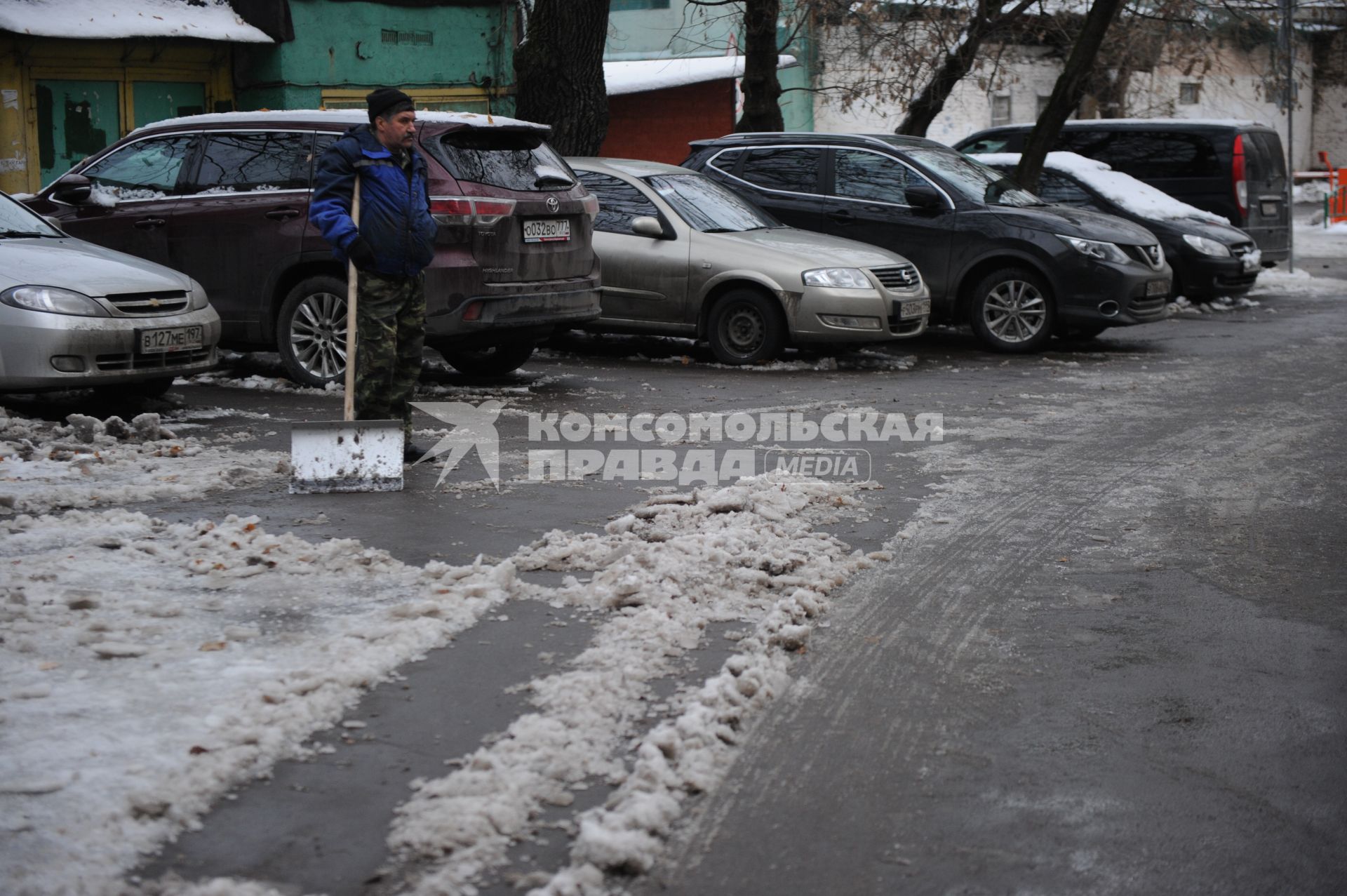 Москва. Дворник убирает снег с тротуара.