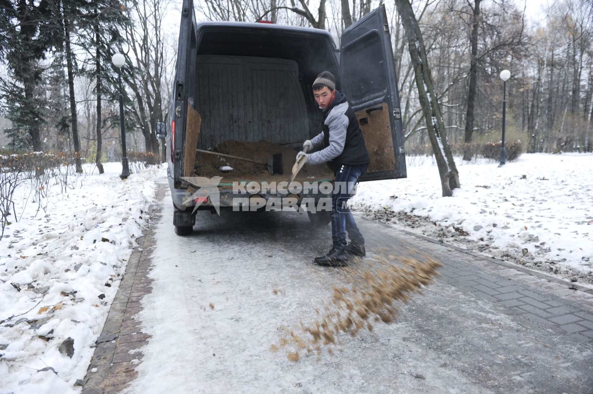 Москва. Дворник посыпает дорожки песком.