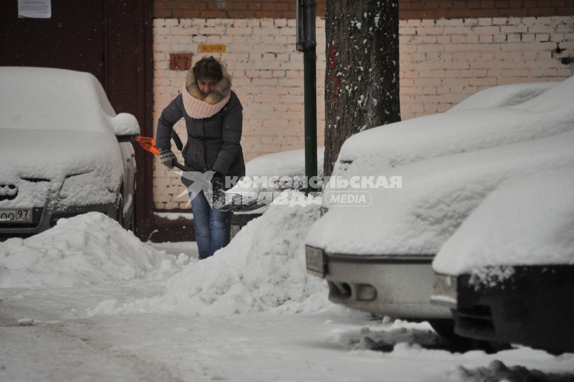 Москва.  Женщина убирает снег во дворе.