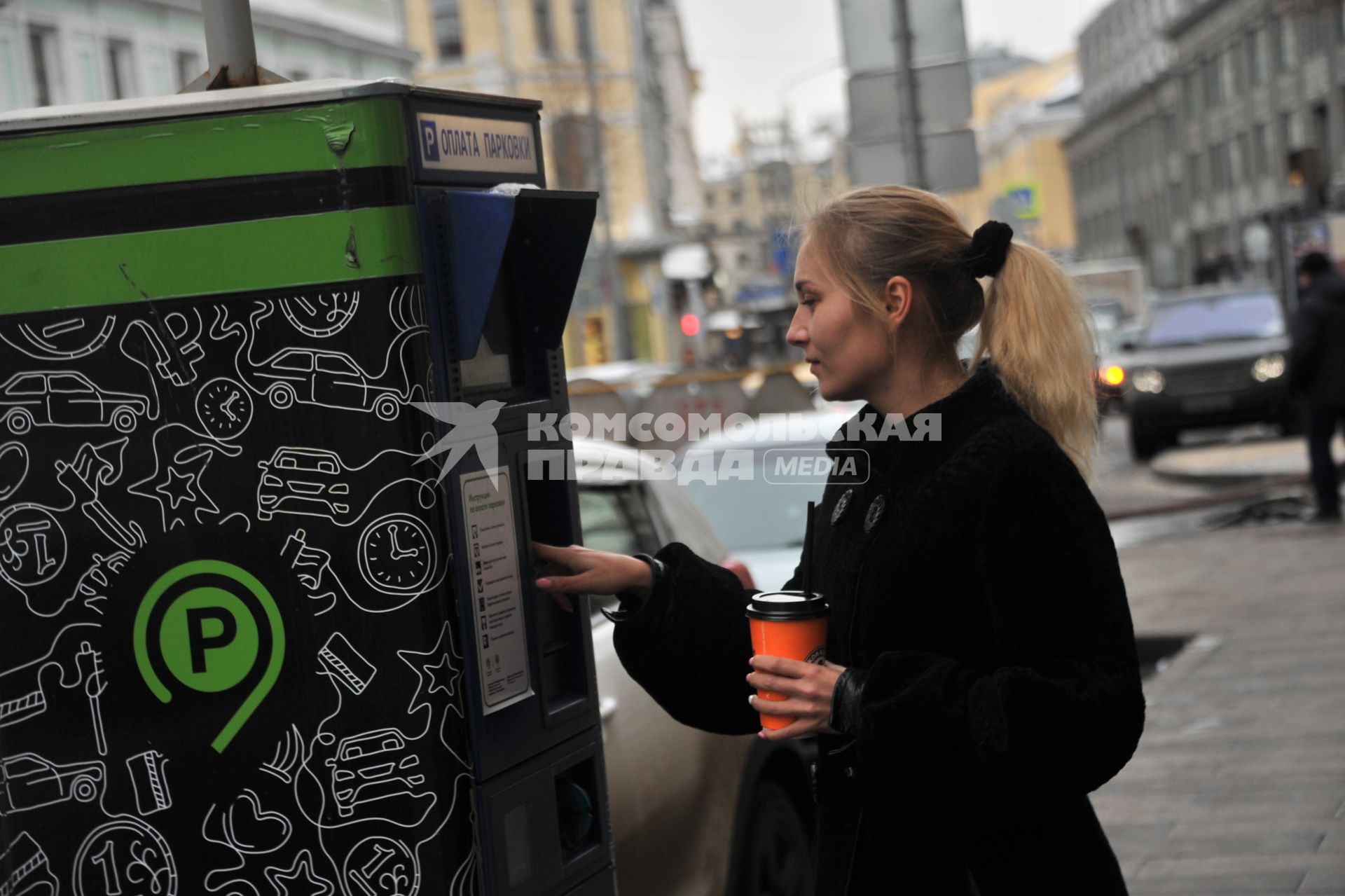 Москва. Девушка оплачивает парковку автомобиля через паркомат.