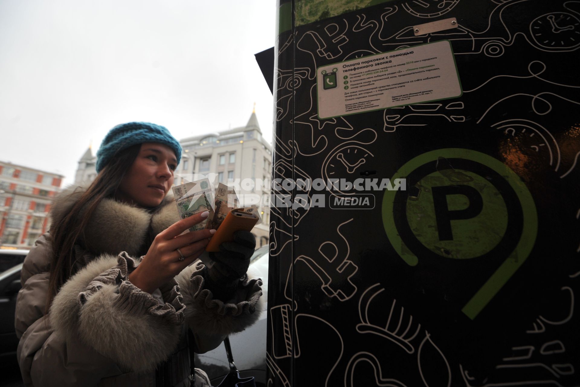 Москва. Девушка оплачивает парковку автомобиля через паркомат.