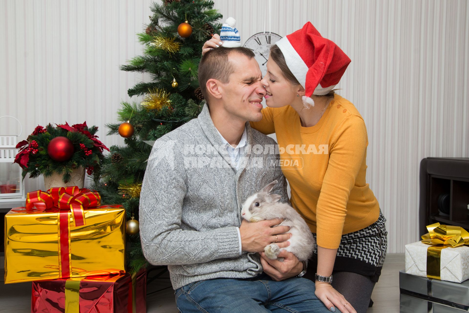 Челябинск.  Девушка и мужчина с кроликом у новогодней елки.