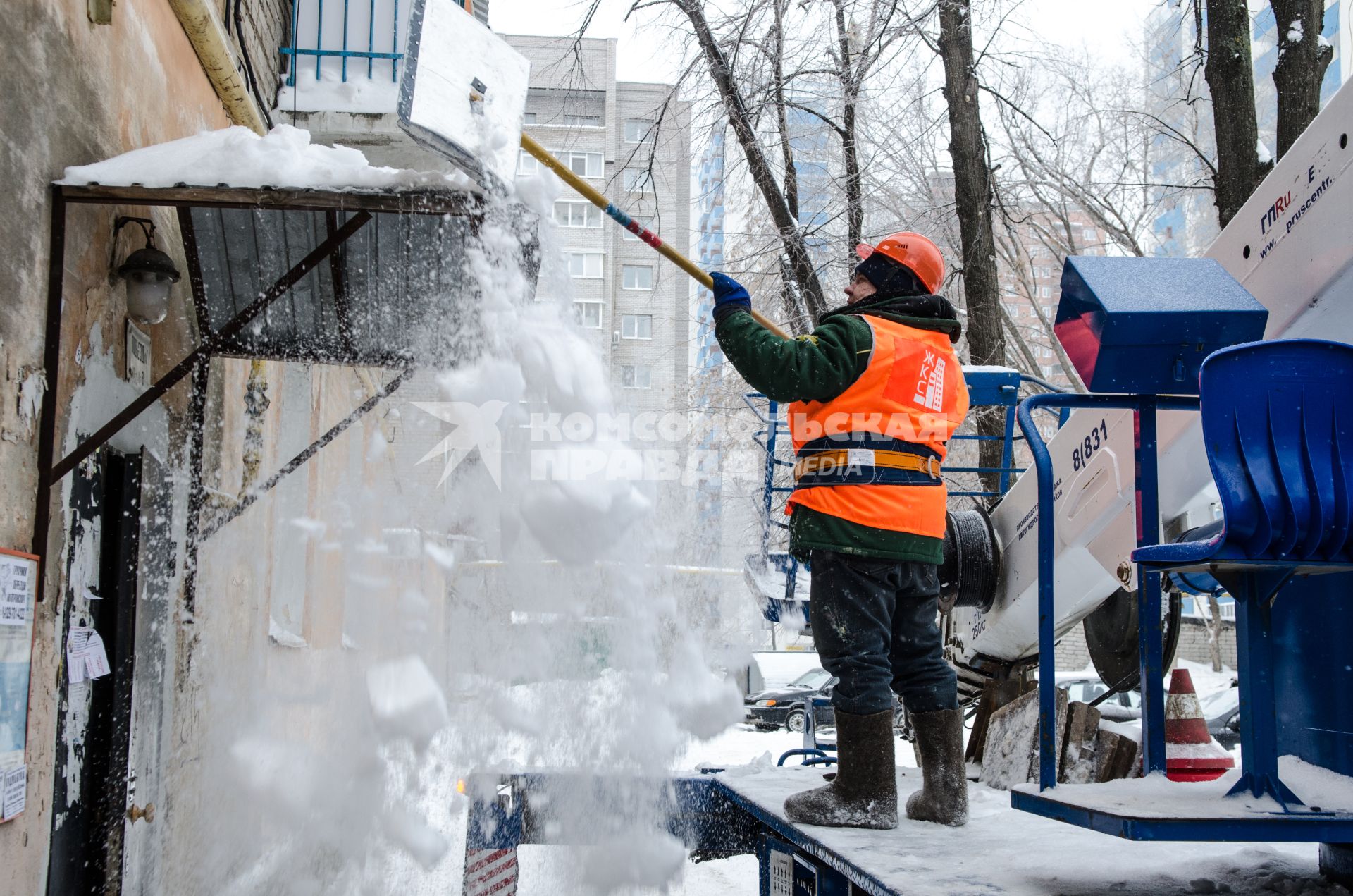 Самара. Сотрудник коммунальной службы счищает снег с козырька подъезда жилого дома.