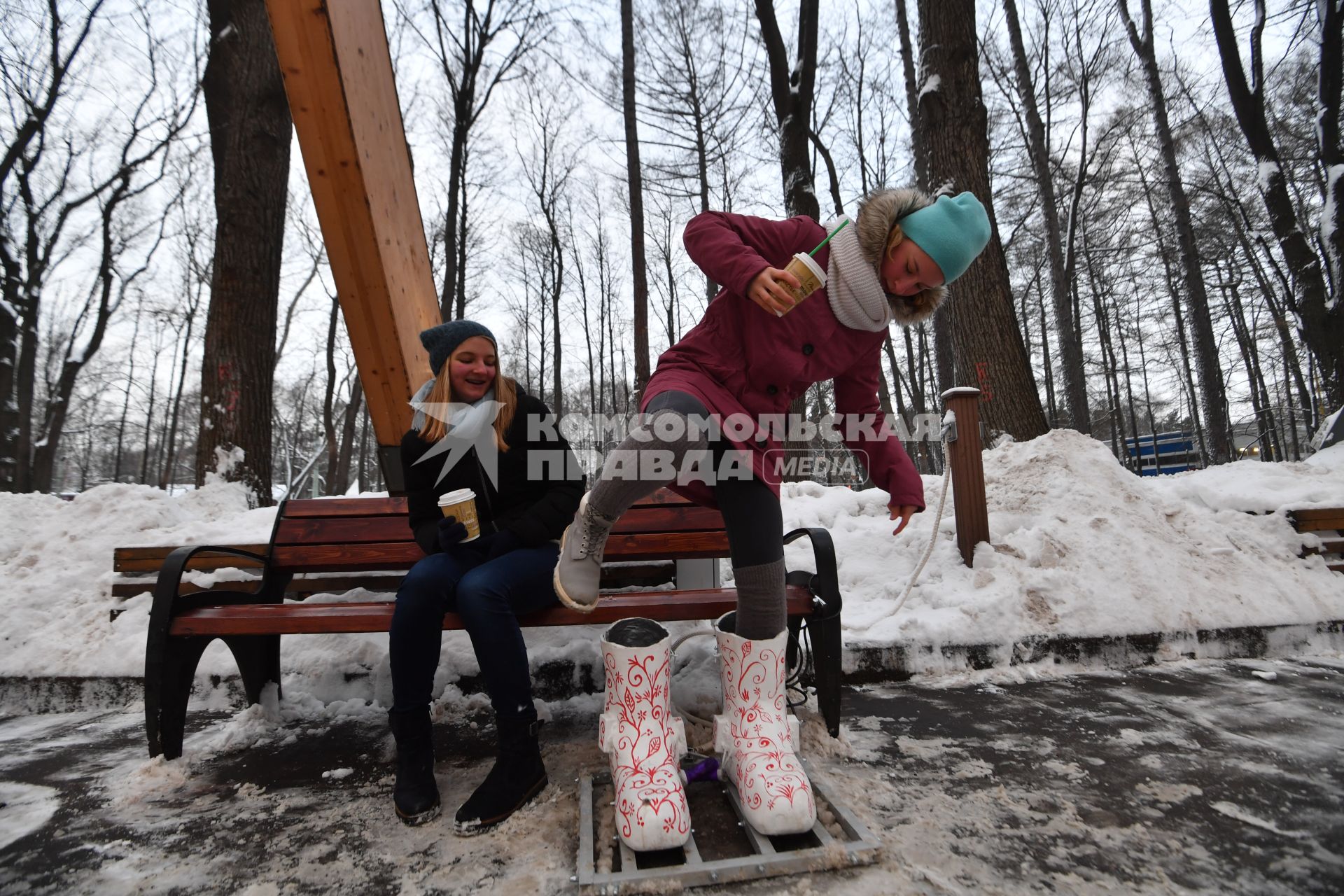 Москва. Девочка греет  ноги в термоваленках, которые установили в парке `Сокольники`на Аллее арок.