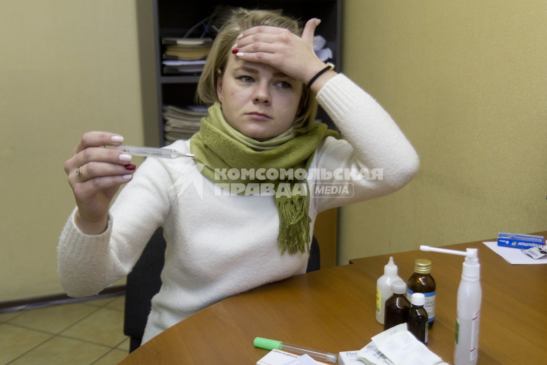 Иркутск. Девушка на рабочем месте в офисе измеряет температуру.