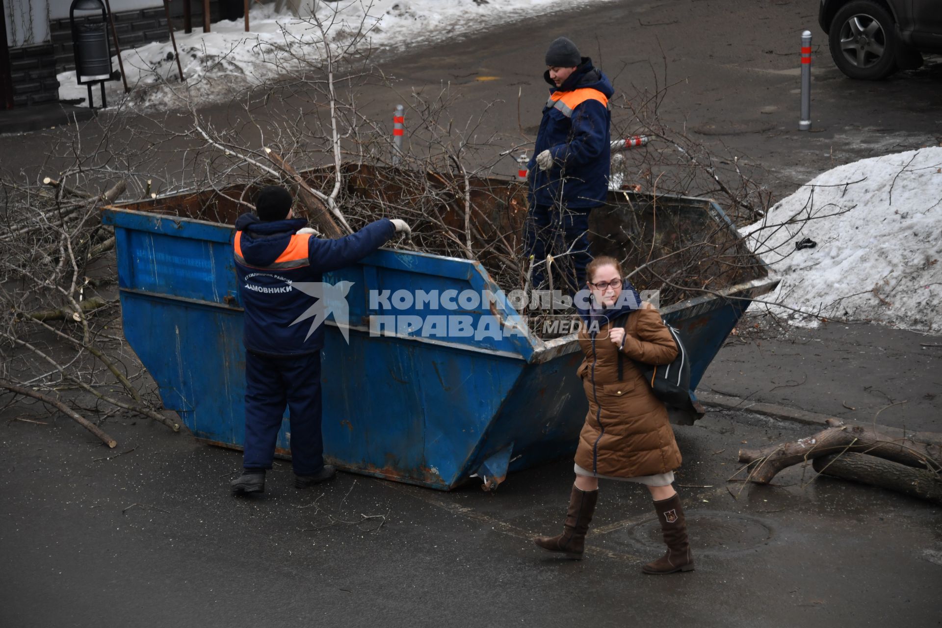 Москва. Сотрудники коммунальных служб  убирают ветки деревьев в мусорный контейнер.