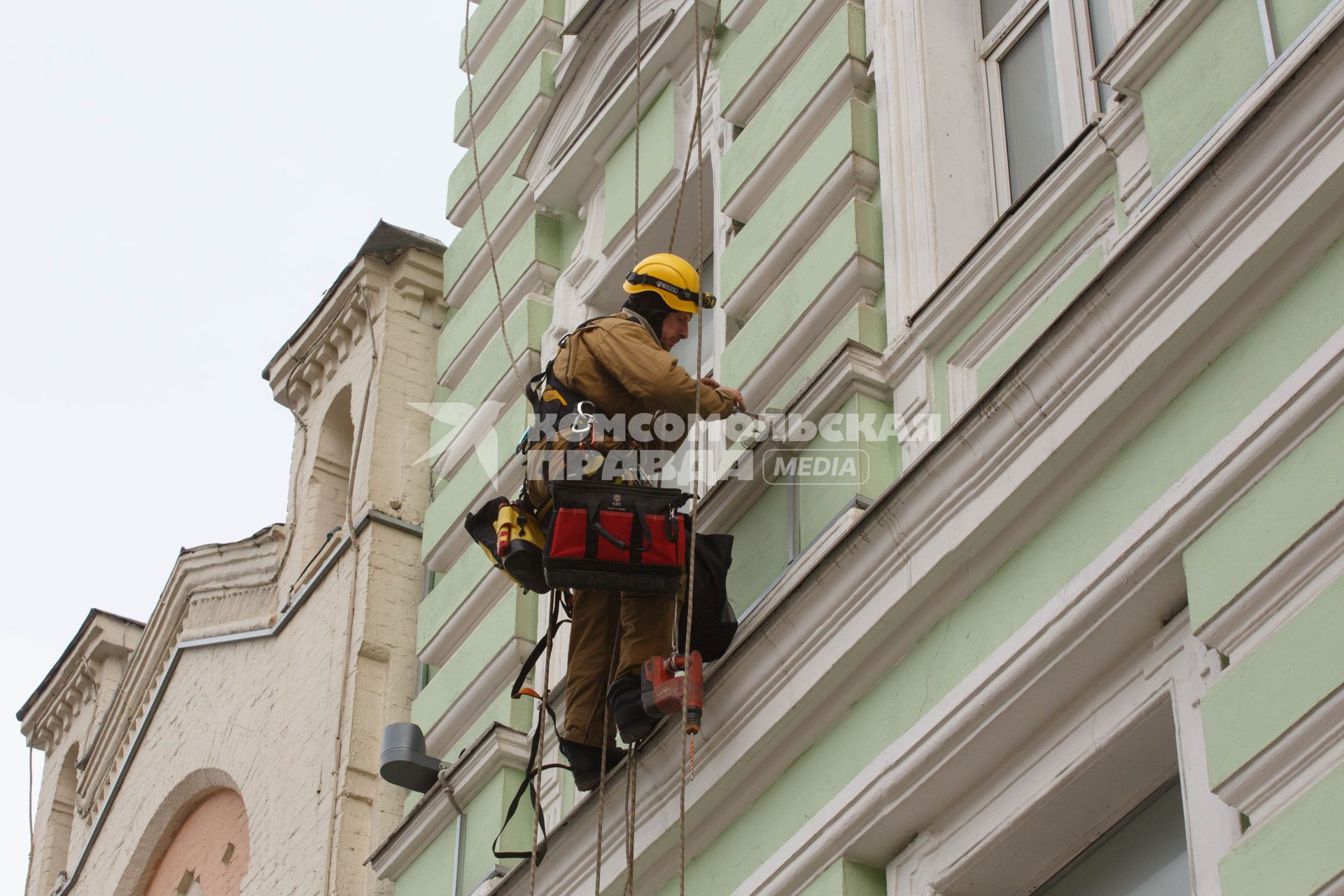Москва. Промышленный альпинист ремонтирует фасад здания.