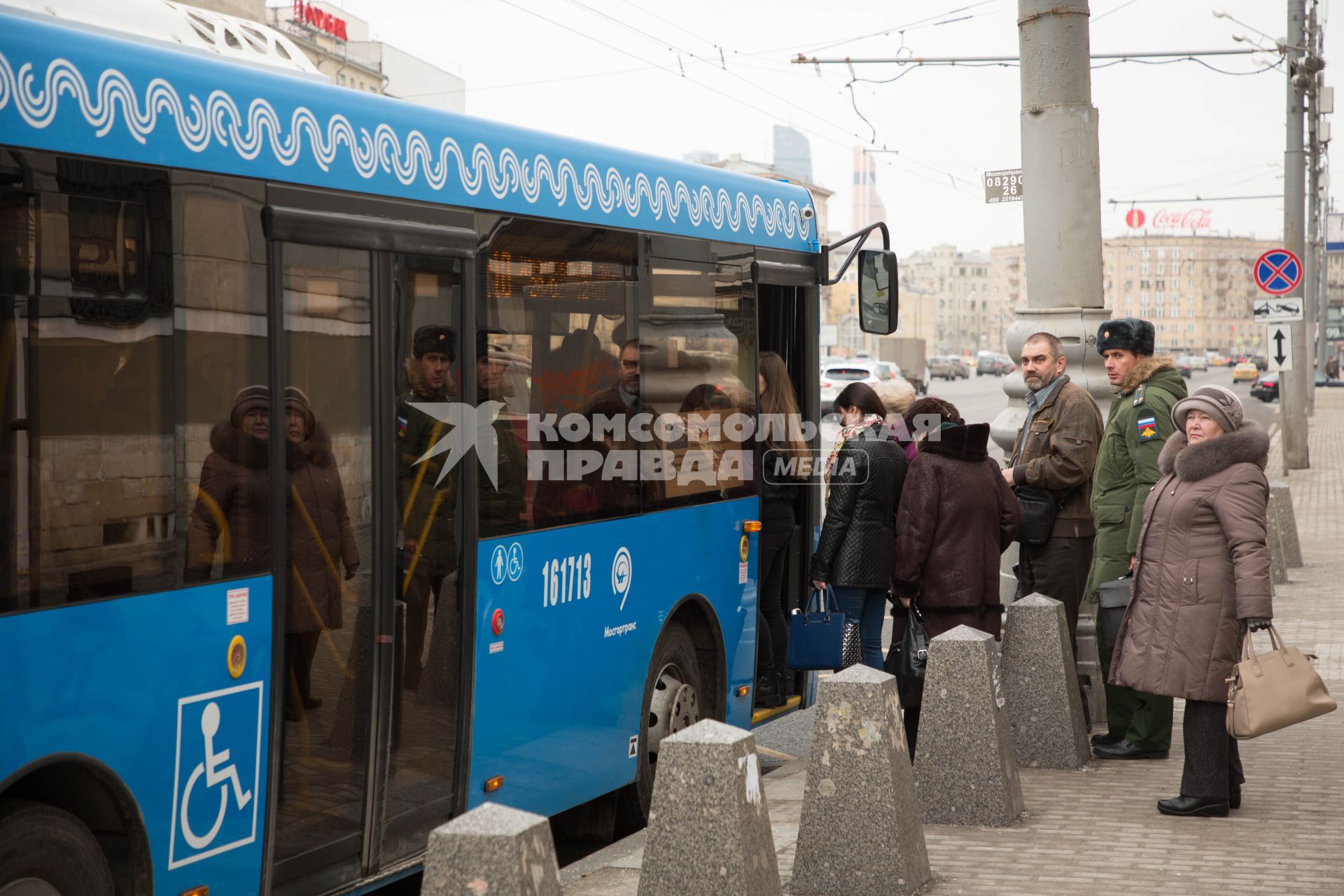 Москва.  Пассажиры садятся в автобус на остановке общественного транспорта.