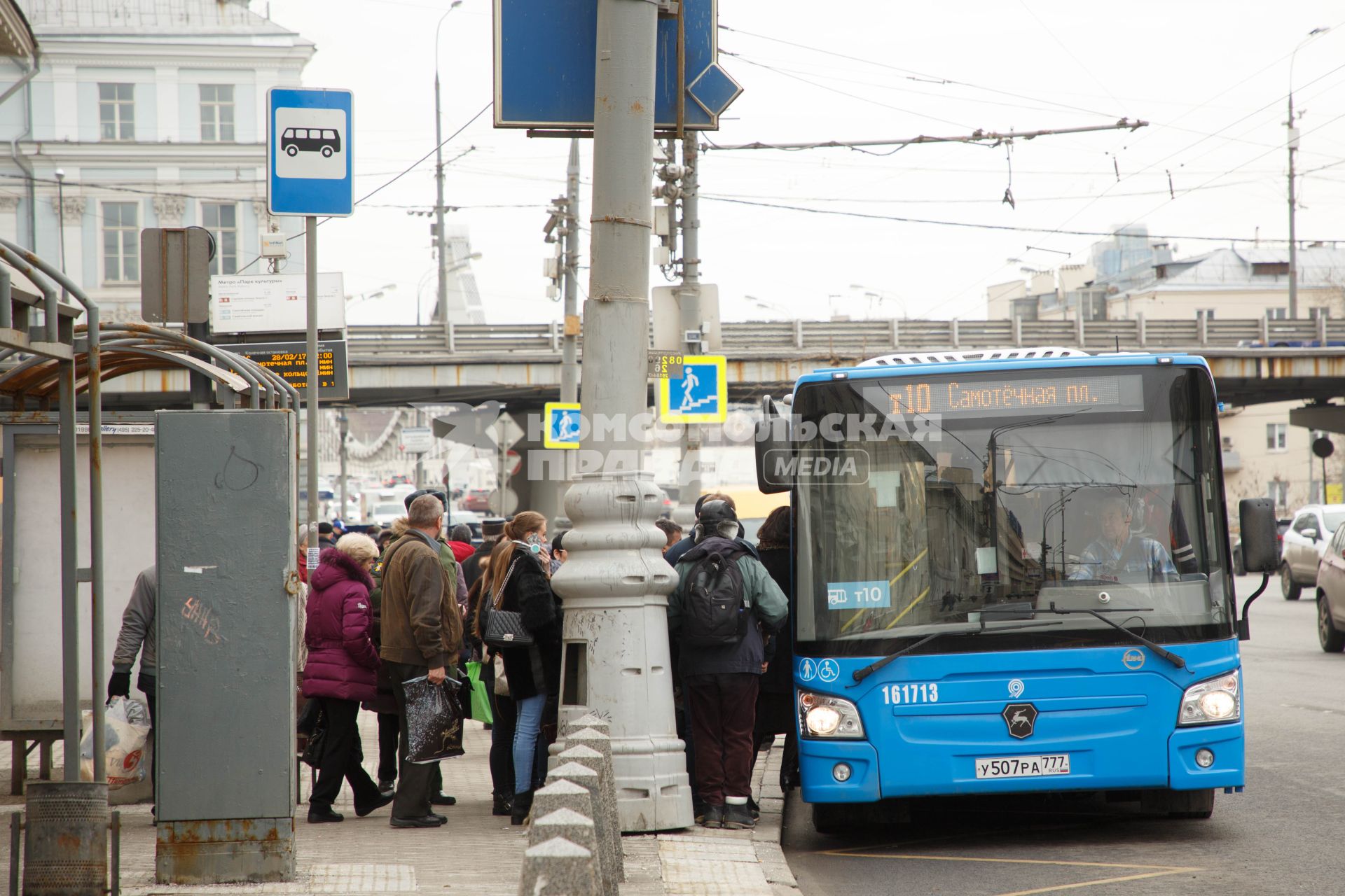 Москва.  Пассажиры садятся в автобус на остановке общественного транспорта.