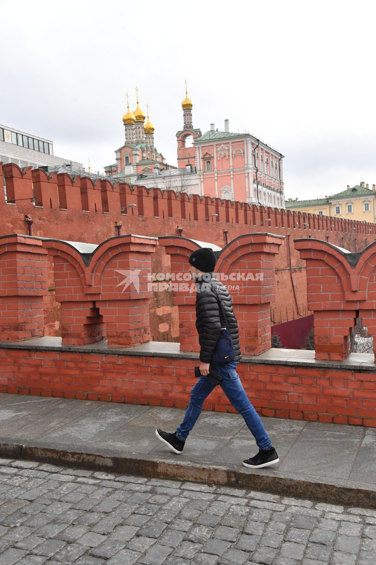 Москва. Молодой человек идет по Троицкому мосту Кремля.