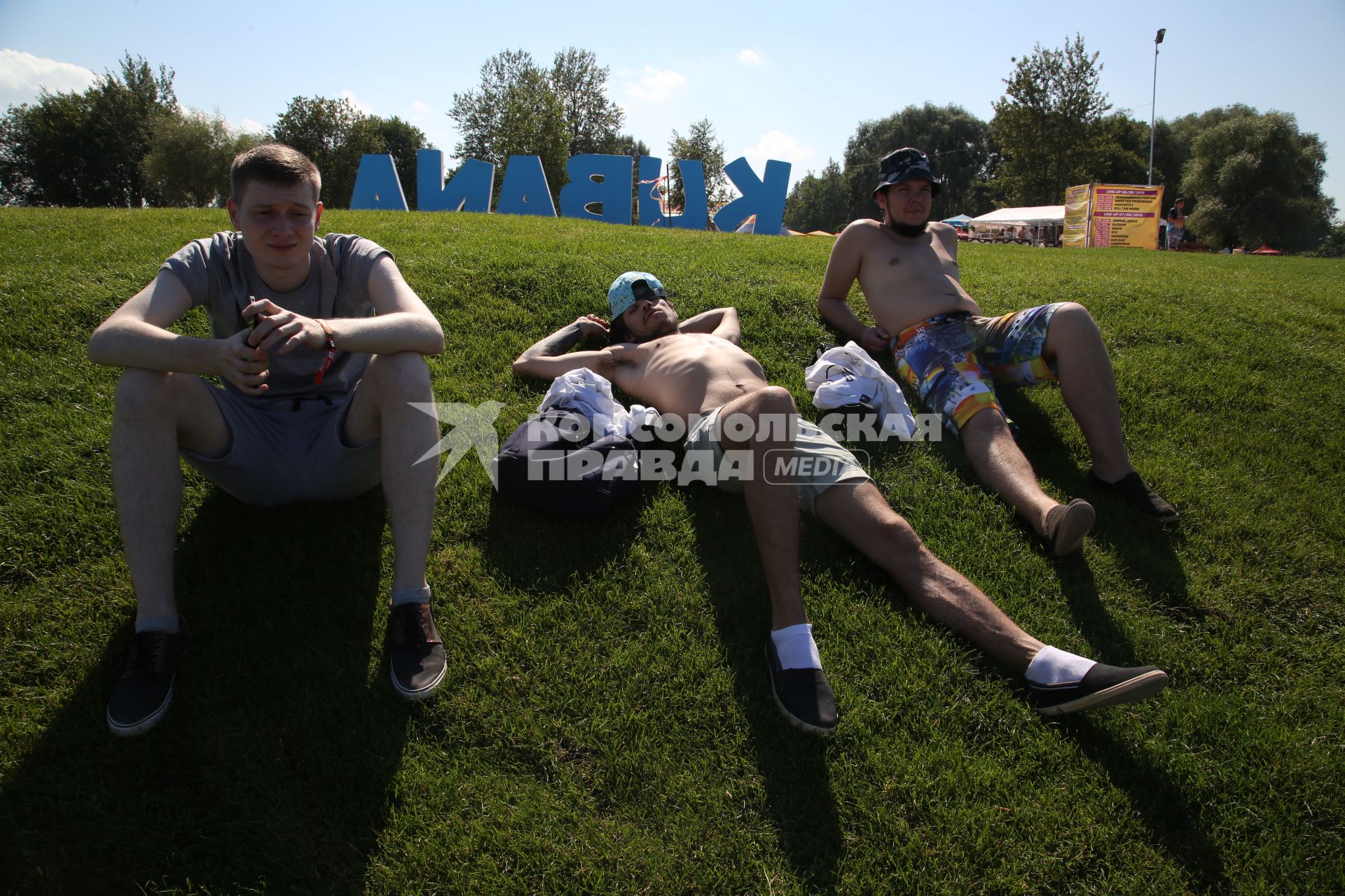 Диск191. Остров Луцавсала. Международный музыкальный фестиваль KUBANA 2015. На снимке: трое ребят отдыхают на газоне на фоне надписи KUBANA