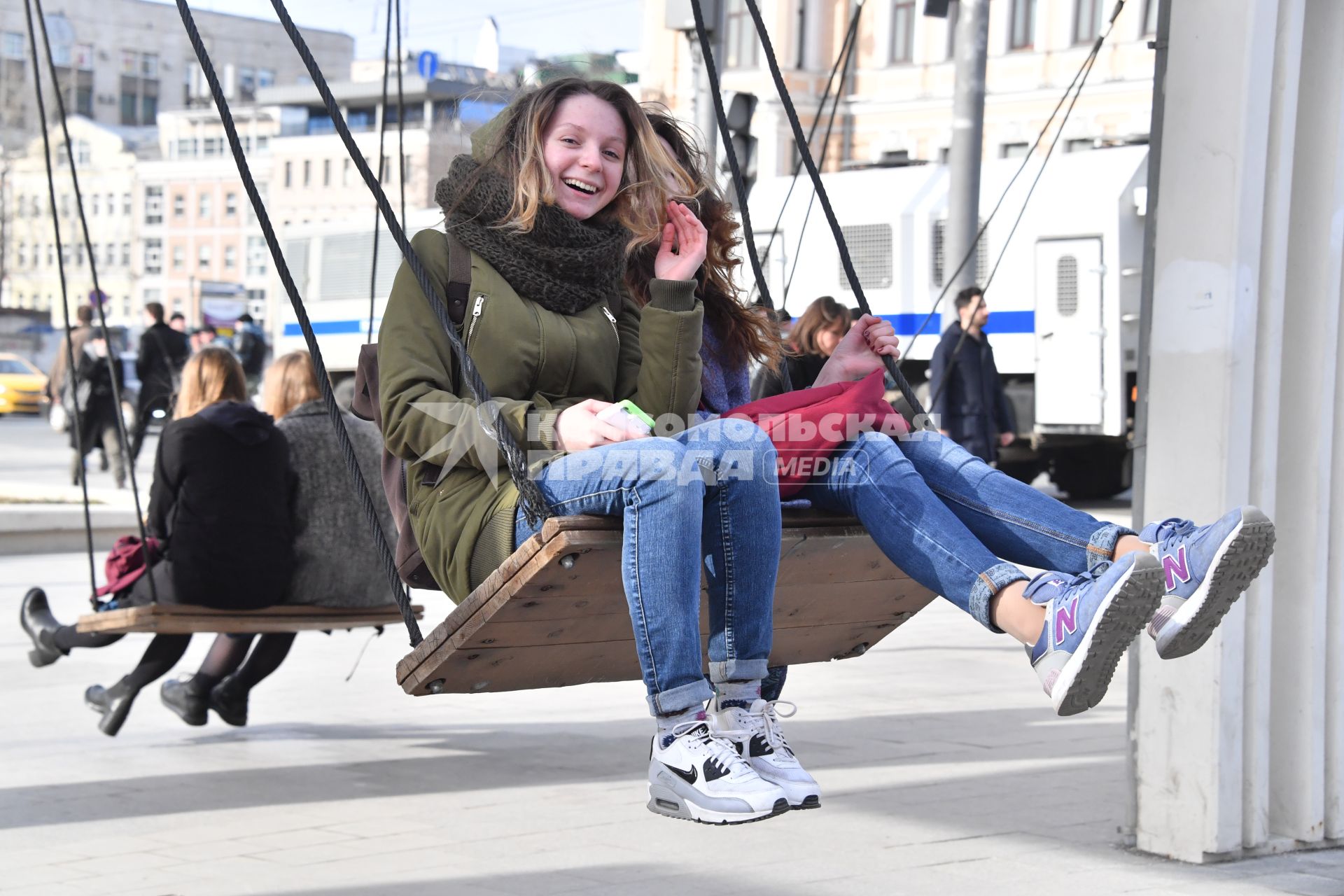 Москва.  Девушки качаются на качелях на Триумфальной  площади.