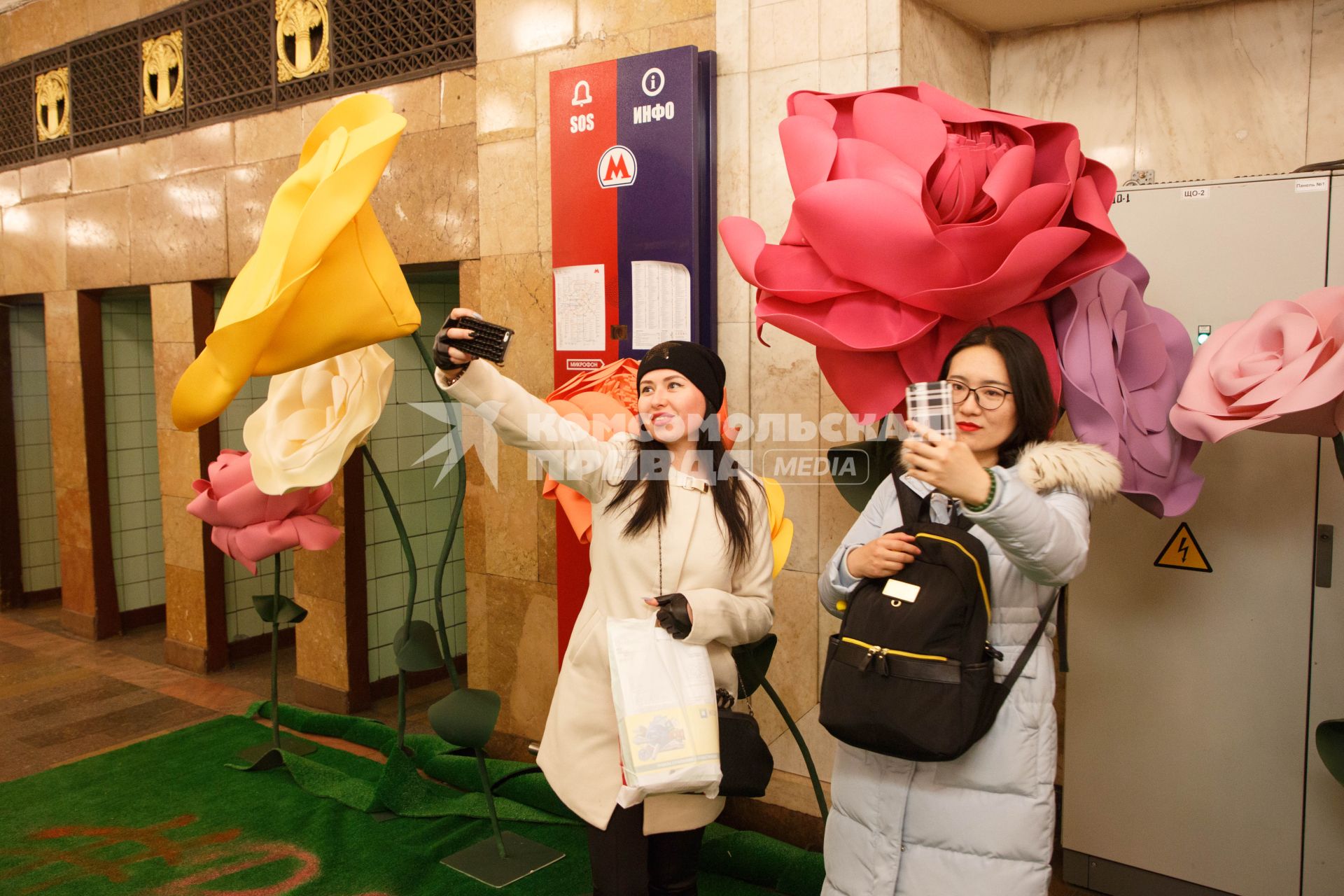 Москва.  Девушки делают селфи на фоне  цветочных композиций, которые появились в метро в канун праздника 8 Марта.