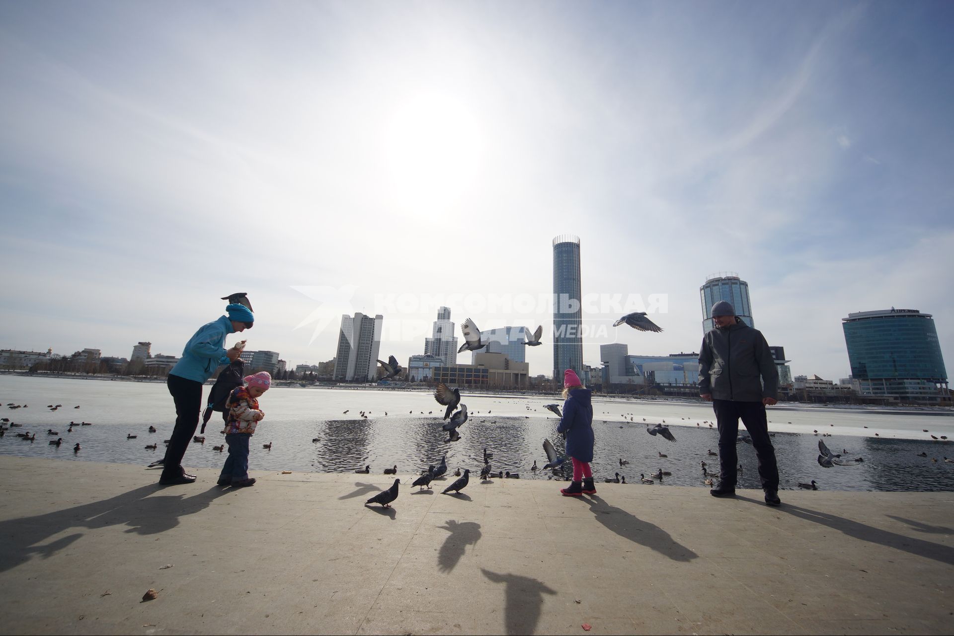 Екатеринбург. Родители с детьми кормят птиц на набережной городского пруда