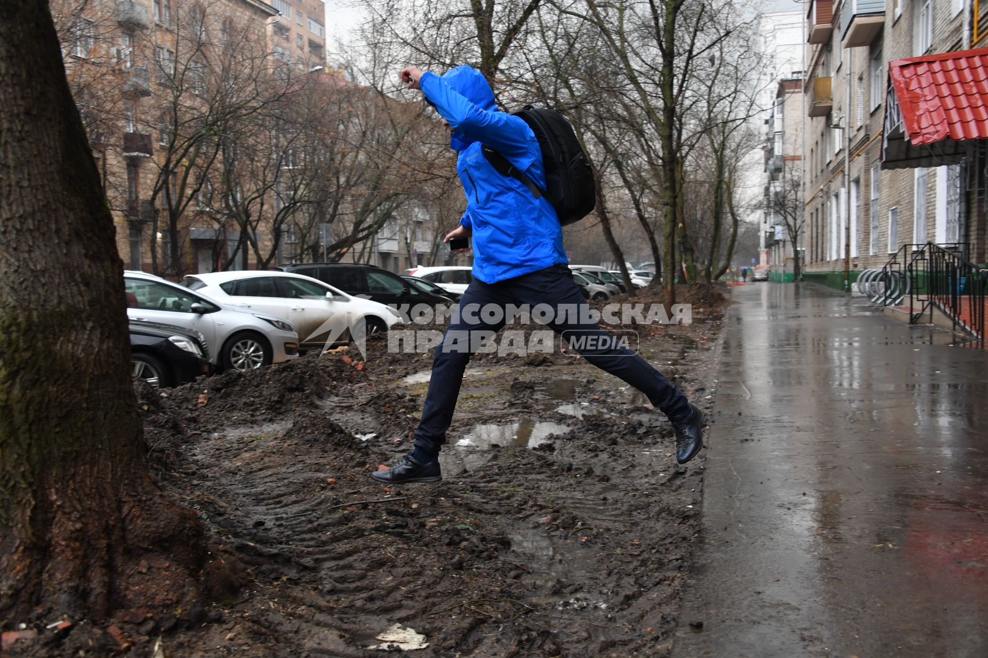 Москва. Мужчина перешагивает через грязные лужи.