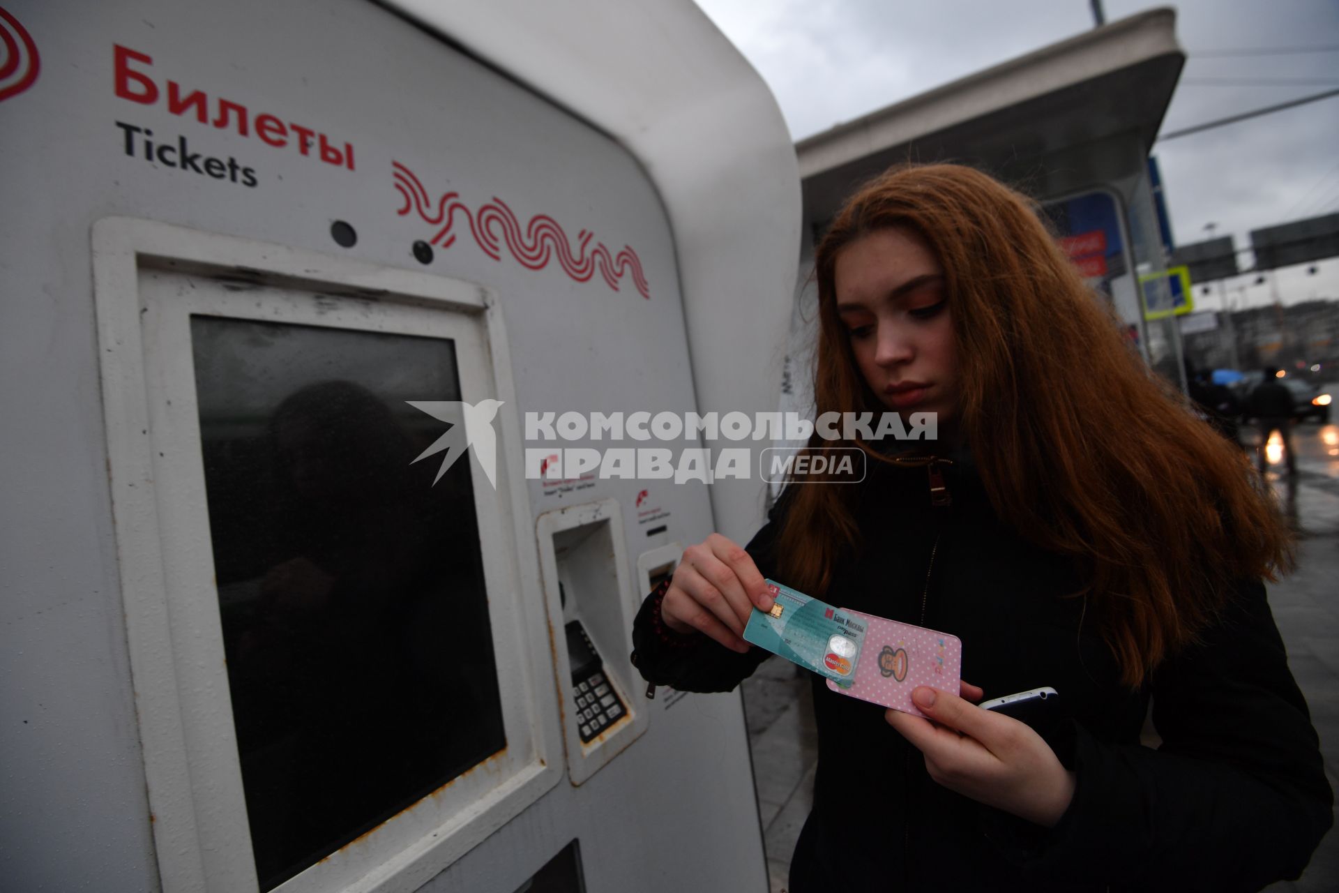 Москва.  Девушка с социальной картой москвича у платежного терминала Мосгортранса.