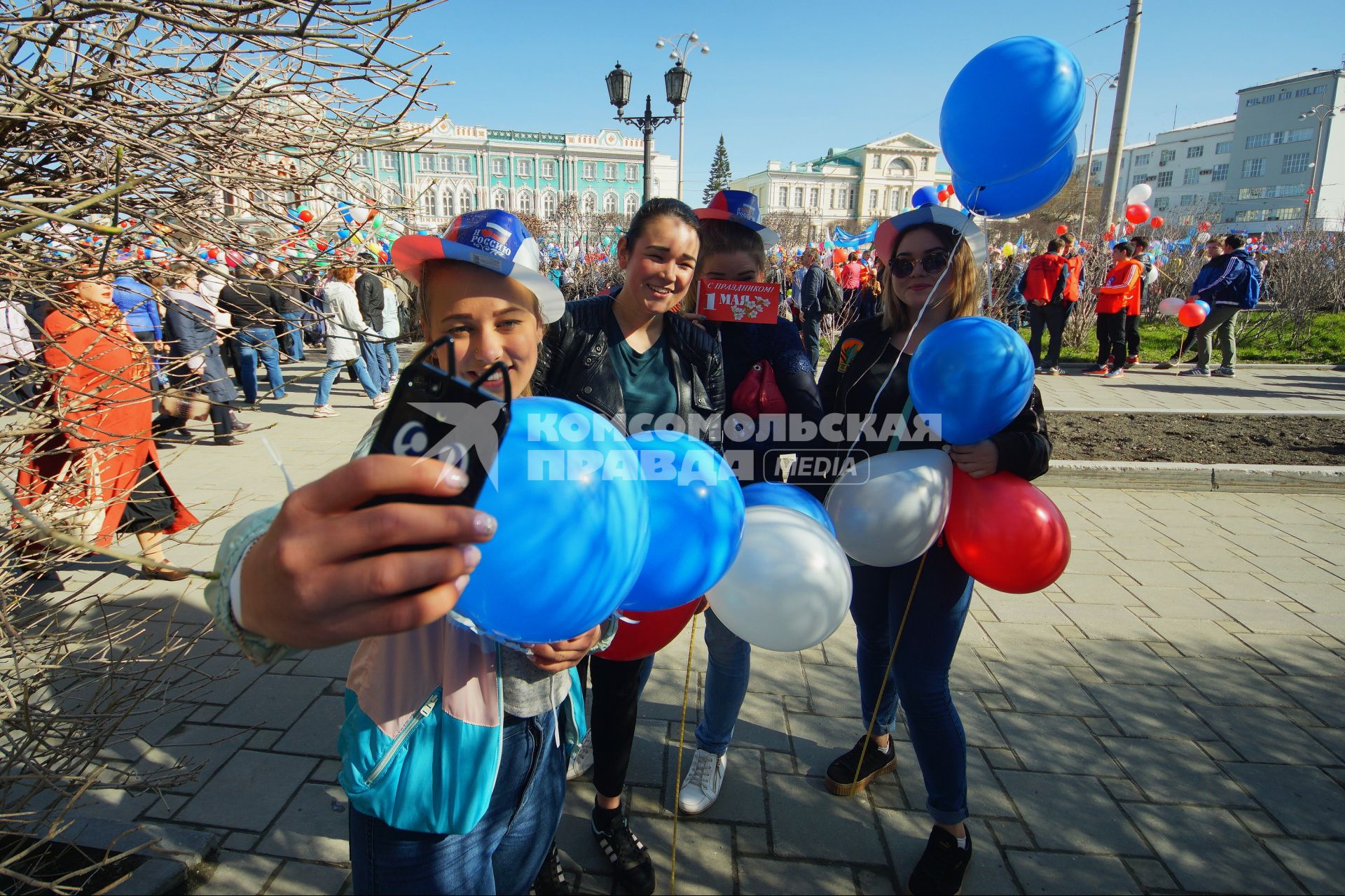 Екатеринбург. Девушки фотографируются на фоне первомайской демонстрации перед началом шествия колонны профсоюзов в день весны и труда.