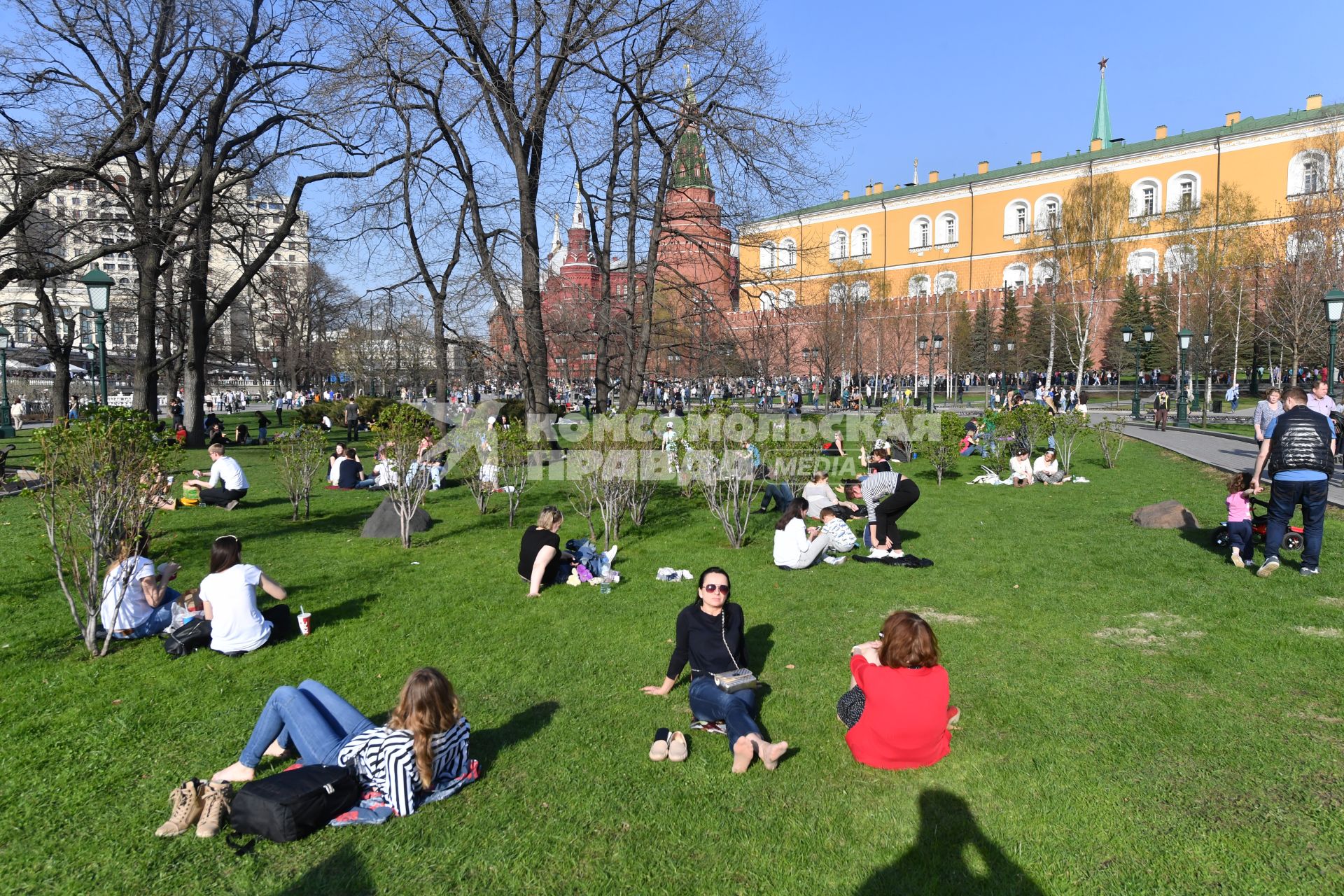 Москва. Молодые люди сидят на газоне  в Александровском саду.