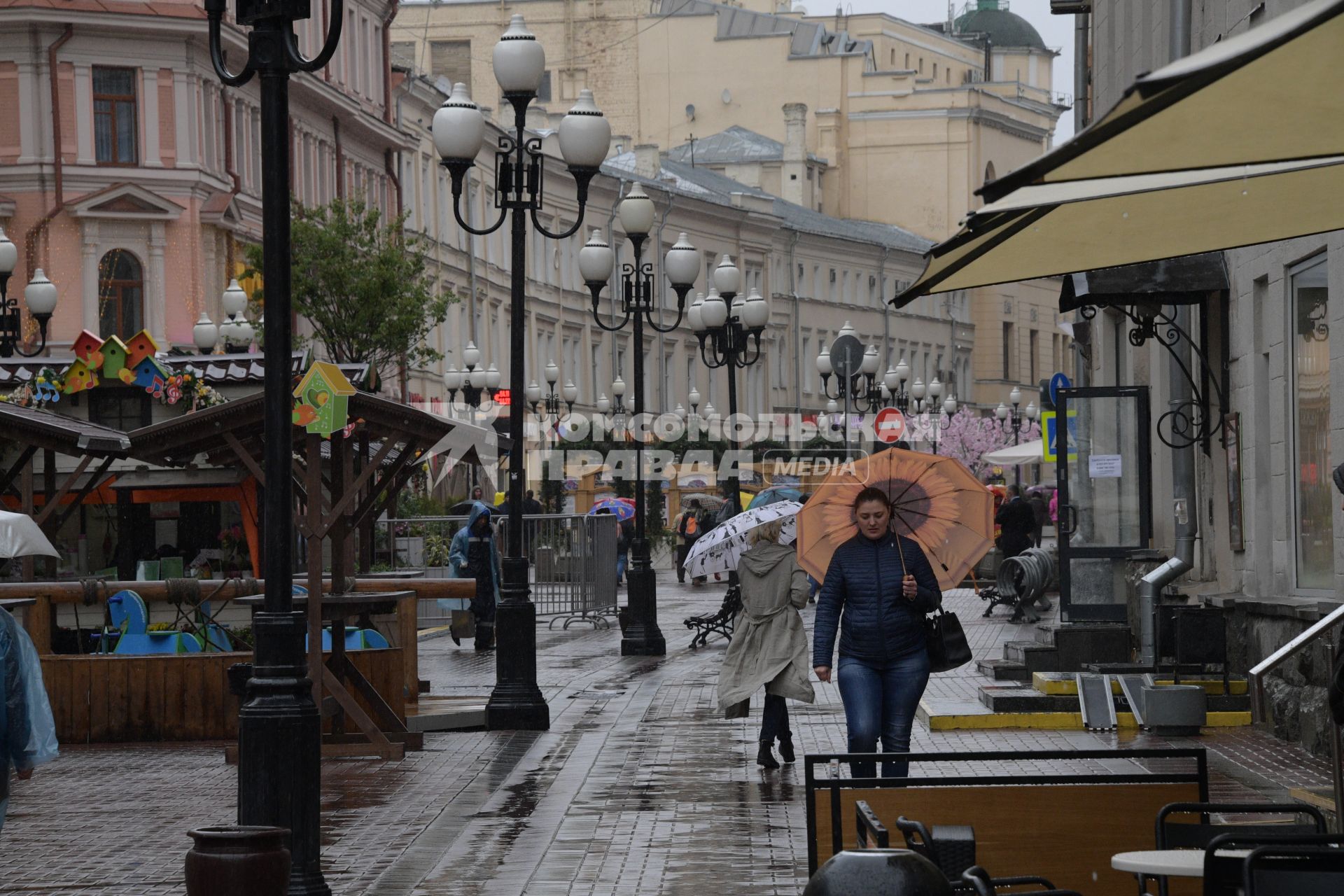 Москва.  Прохожие под дождем идут по Старому Арбату.