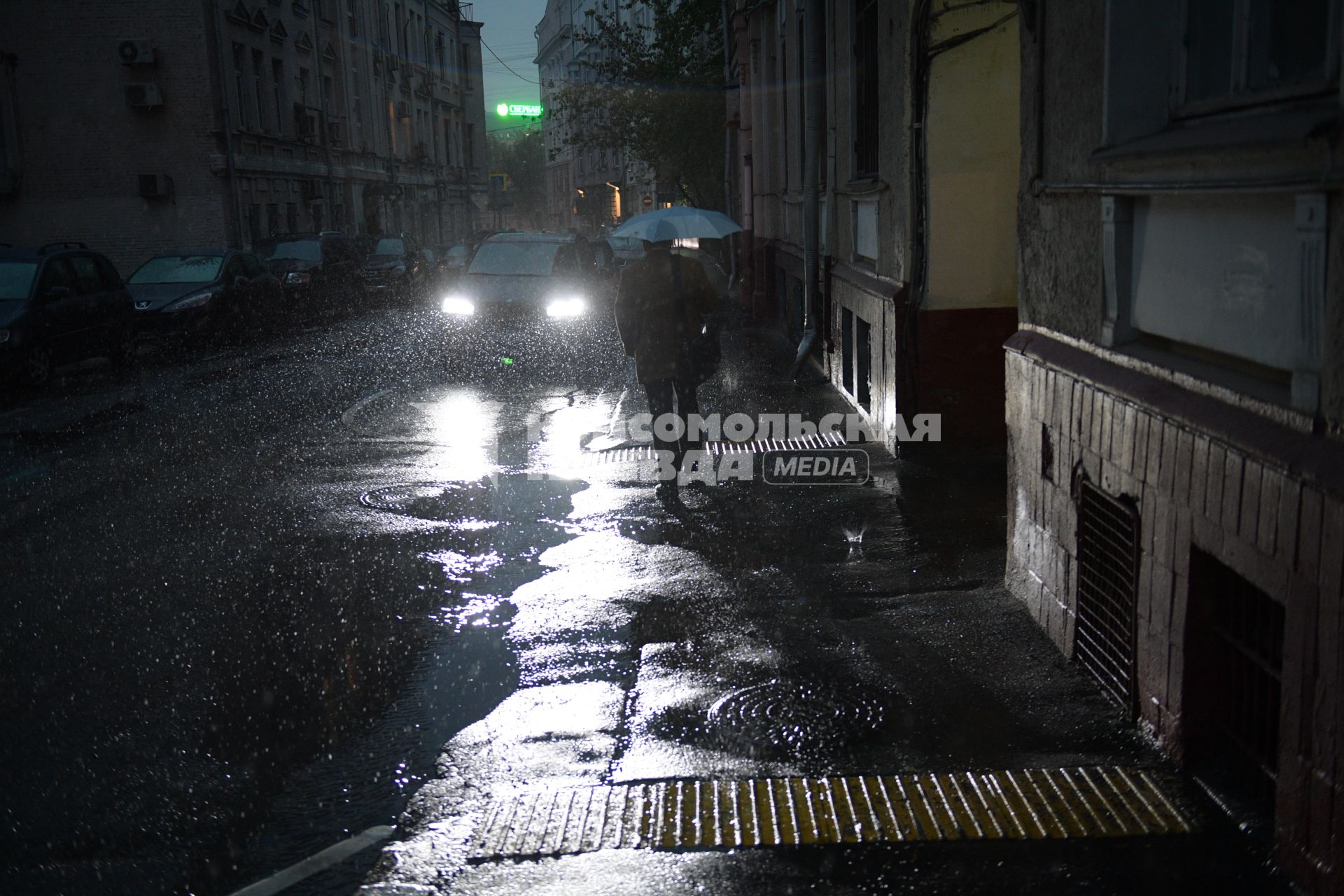 Москва. Мужчина идет по улице под зонтом.