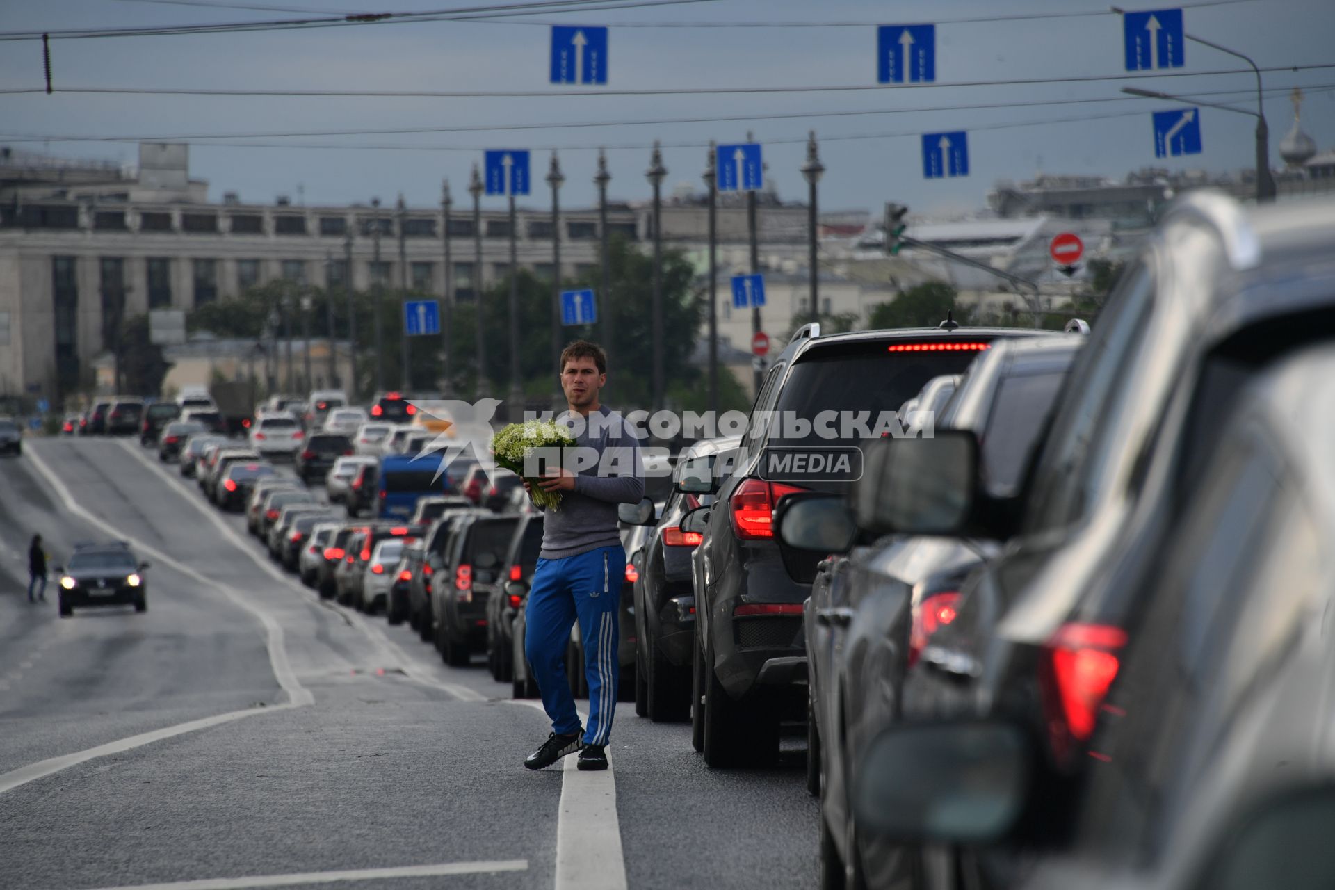 Москва. Мужчина торгует цветами на дороге среди машин.