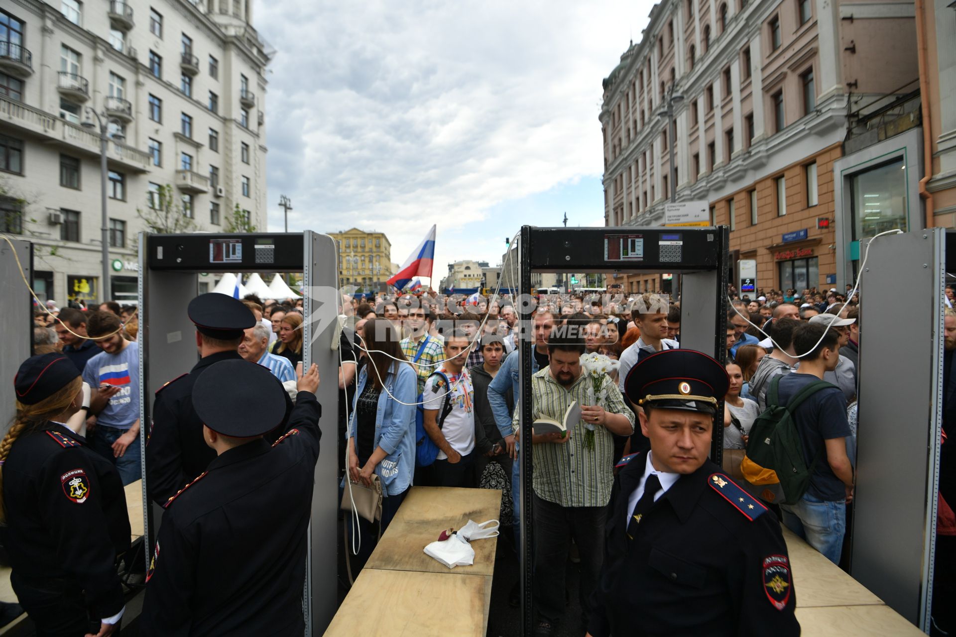 Москва. Полицейские пропускают людей через  рамки металлоискателя.