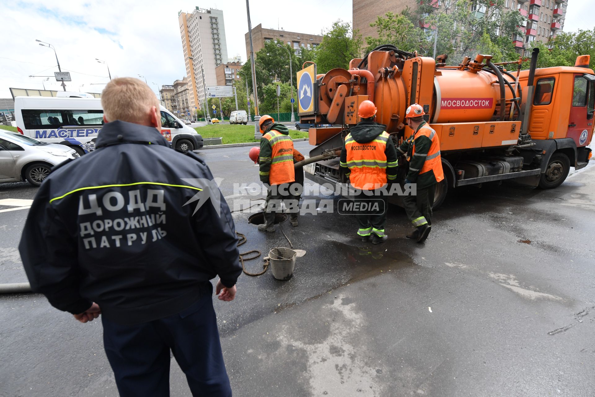 Москва.  Сотрудник дорожной службы ЦОДД  наблюдает за работой сотрудников ГУП `Мосводосток`   на Сущевском валу.