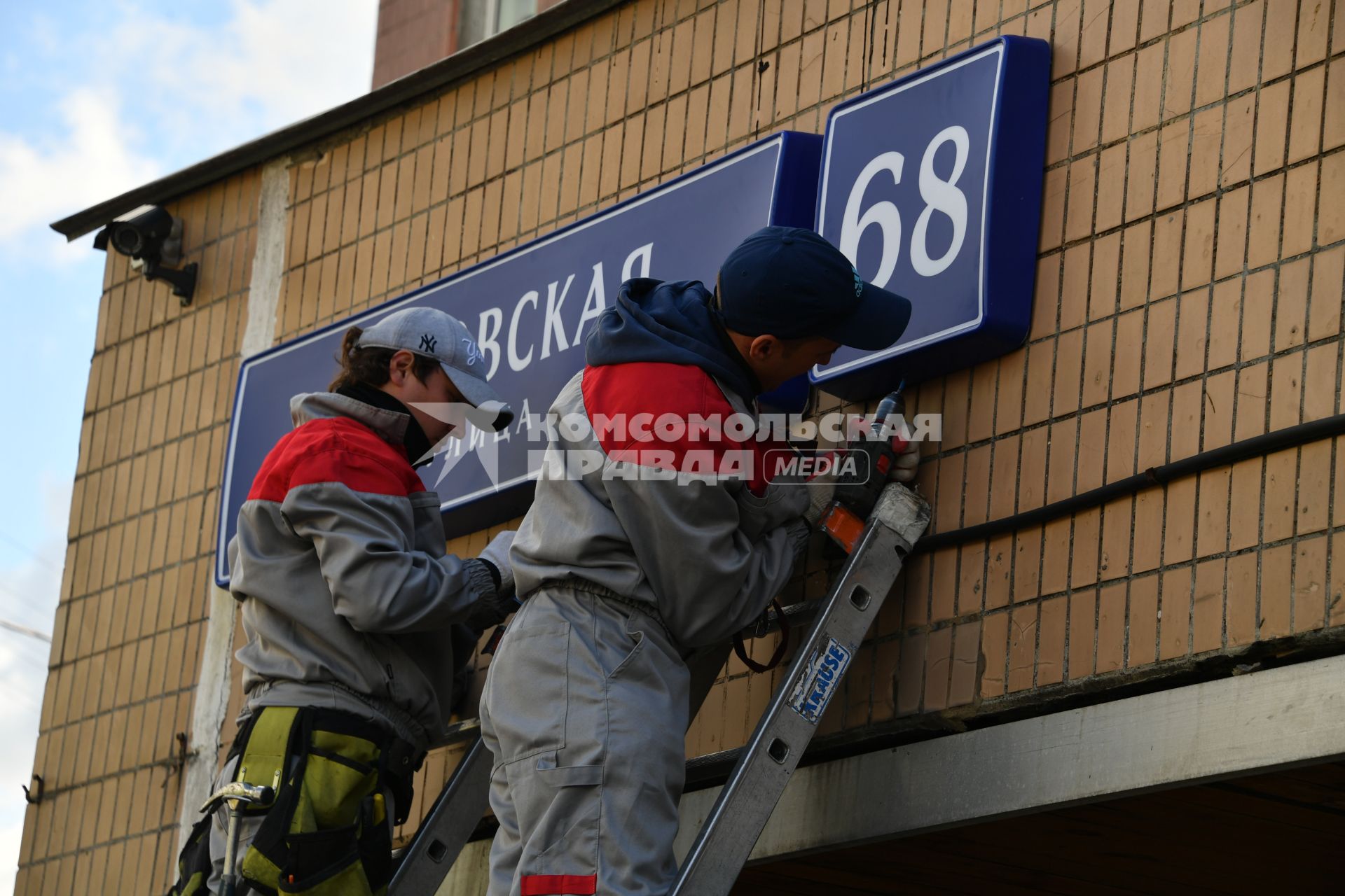 Москва. Рабочие устанавливают домовой указатель на здании Перовской улицы.