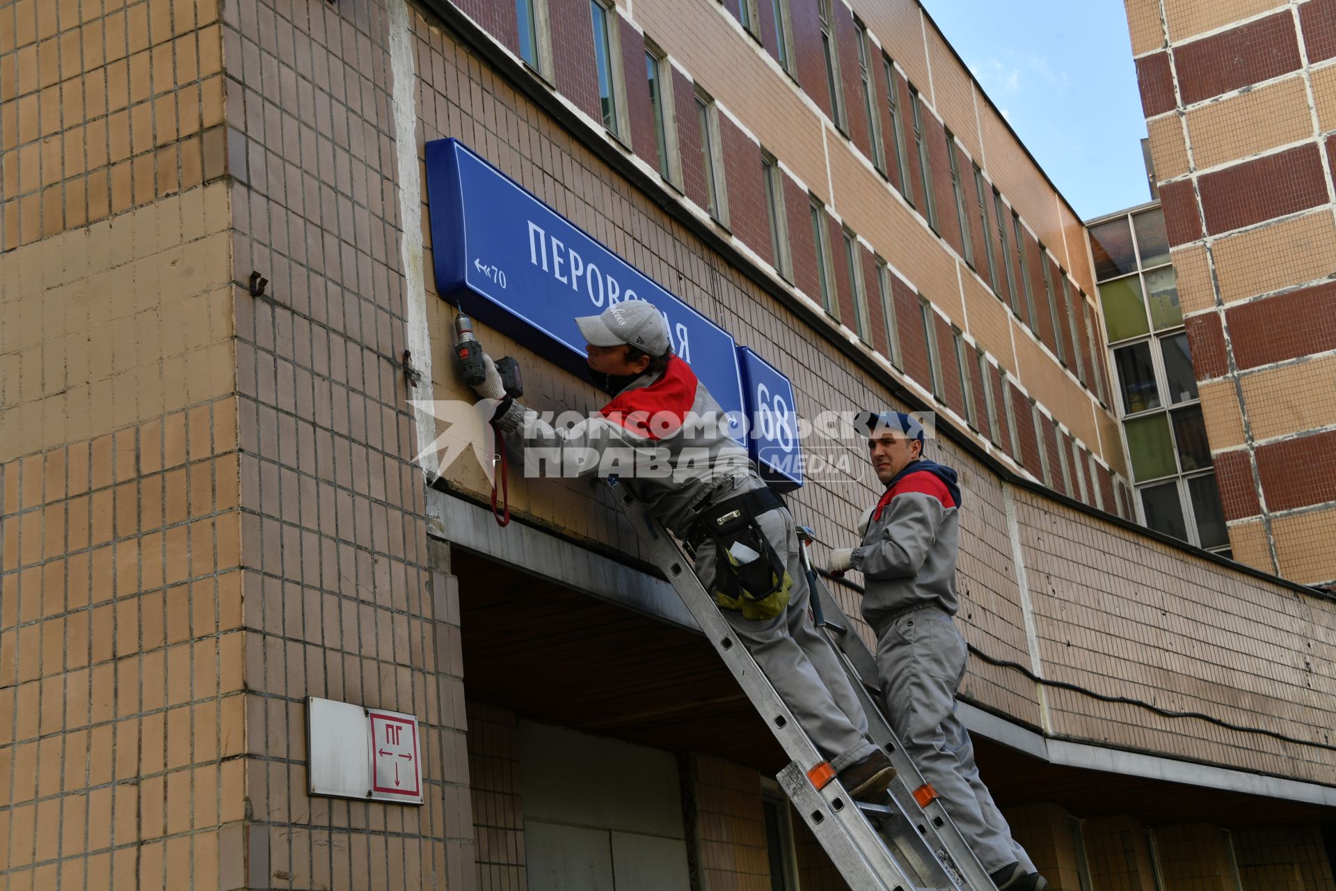 Москва. Рабочие устанавливают домовой указатель на здании Перовской улицы.