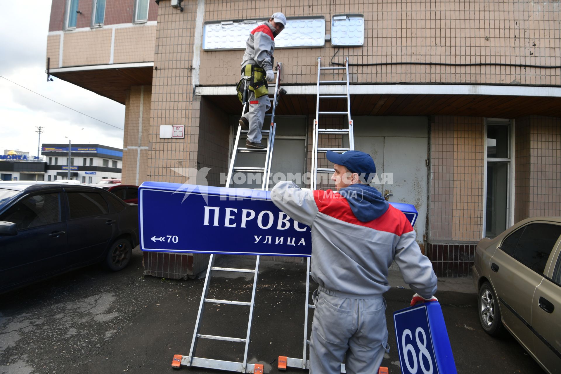 Москва. Рабочие устанавливают домовой указатель на здании Перовской улицы.