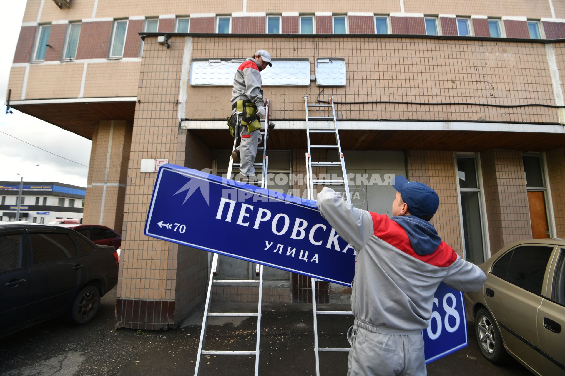 Москва. Рабочие устанавливают домовой указатель на здании Перовской улицы.