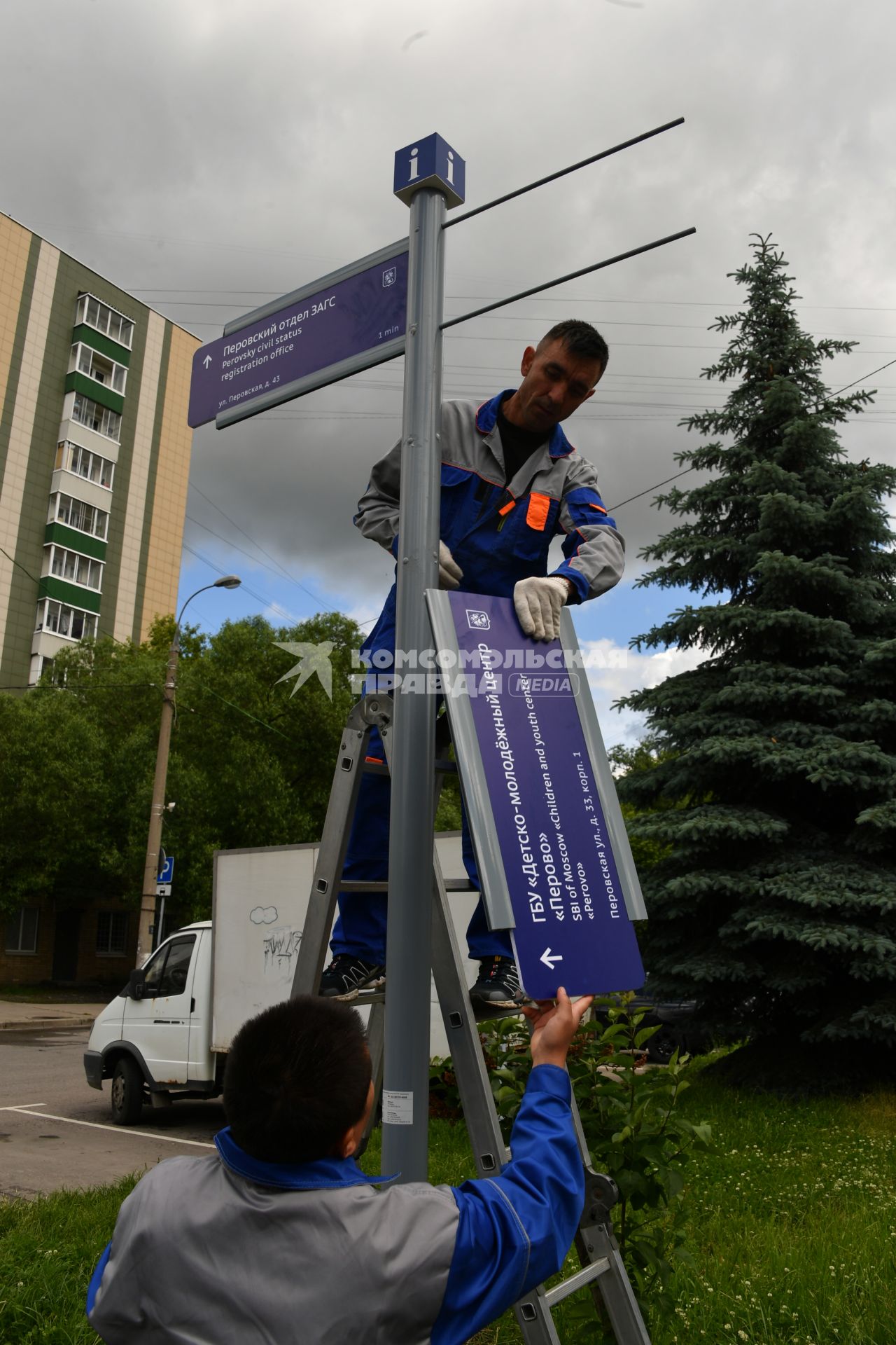 Москва. Рабочие устанавливают уличный указатель на Перовской улице.