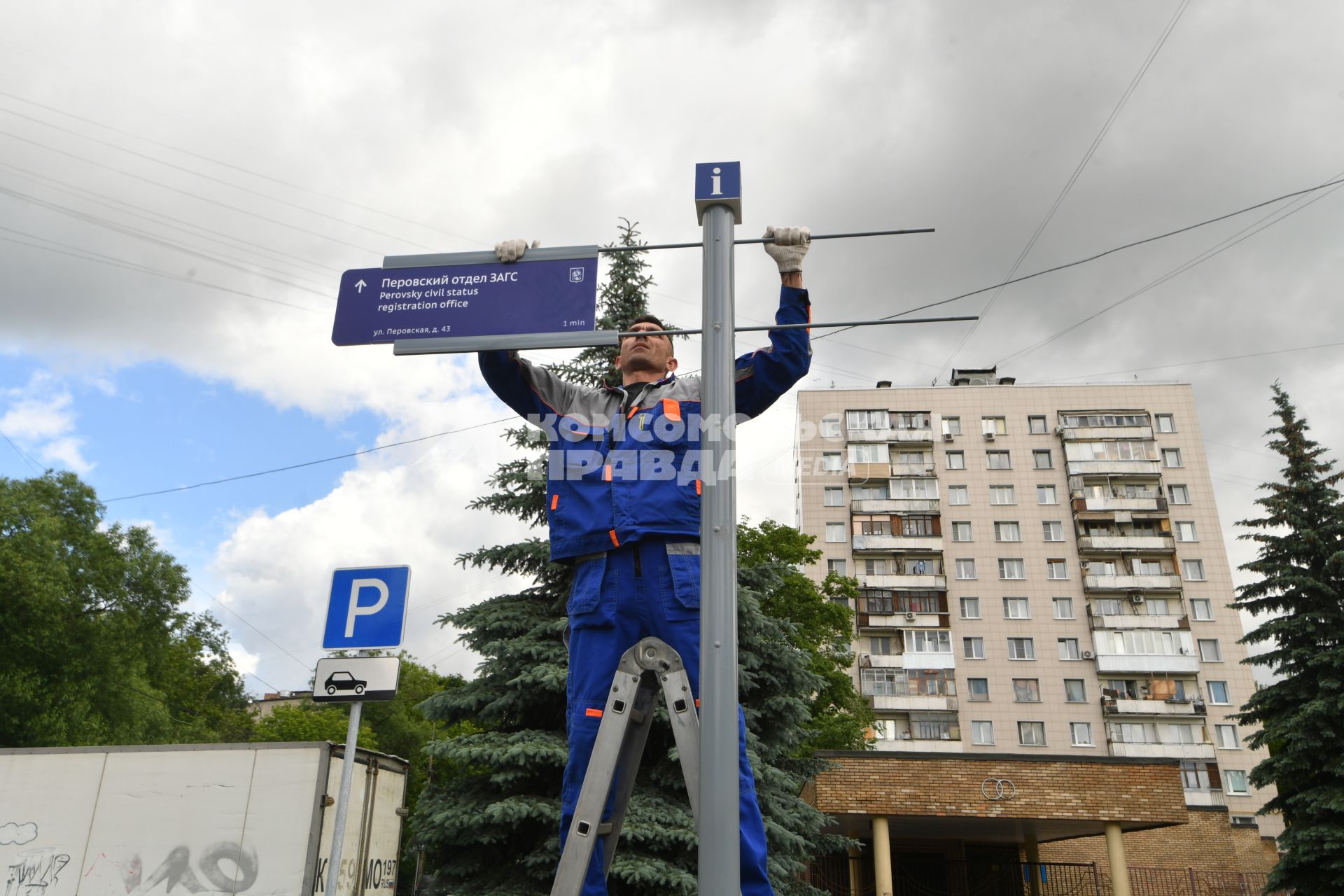 Москва. Рабочий устанавливает уличный указатель на Перовской улице.