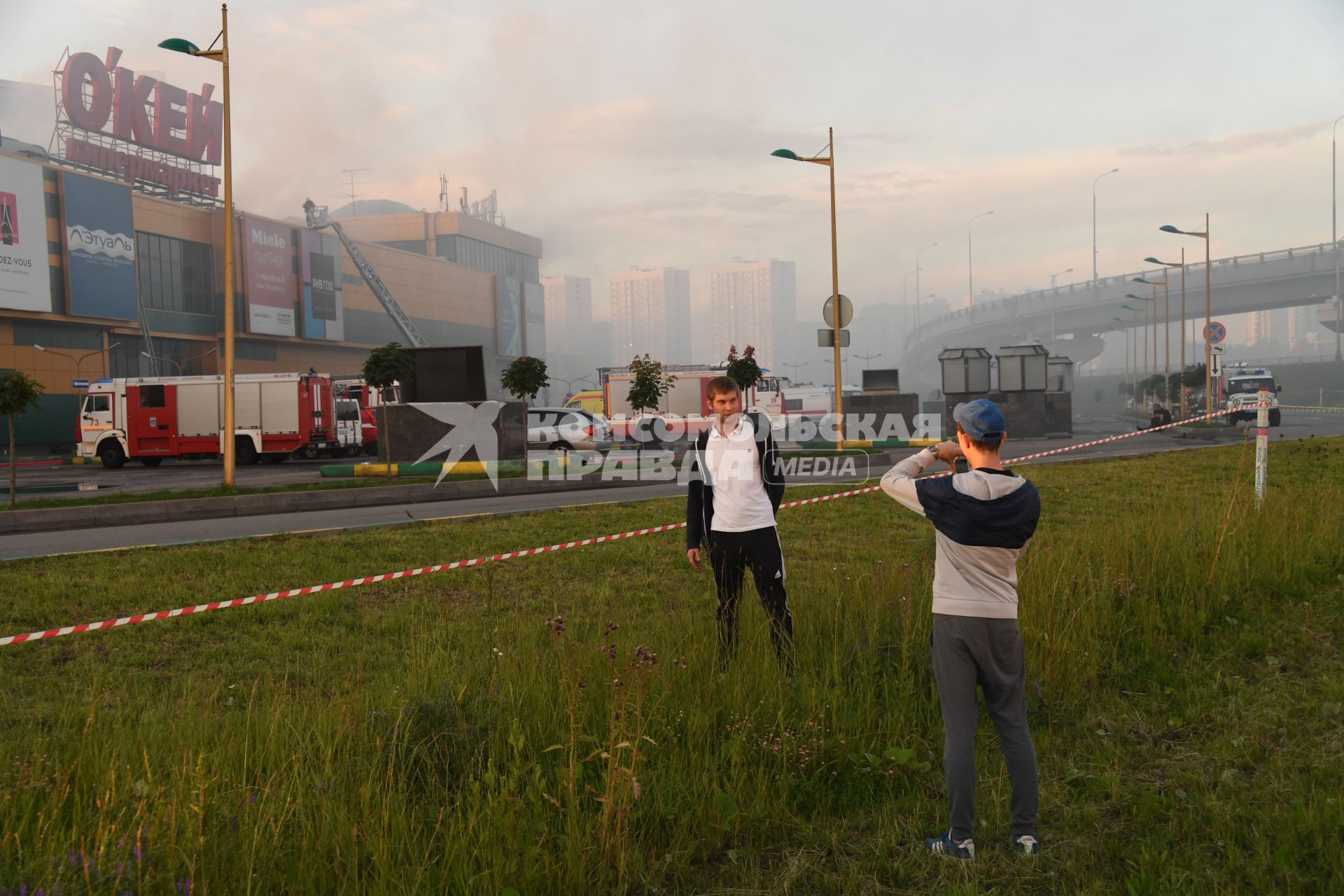 Москва.  Прохожие наблюдают за тушением пожара  в здании торгового центра `РИО` на Дмитровском шоссе.