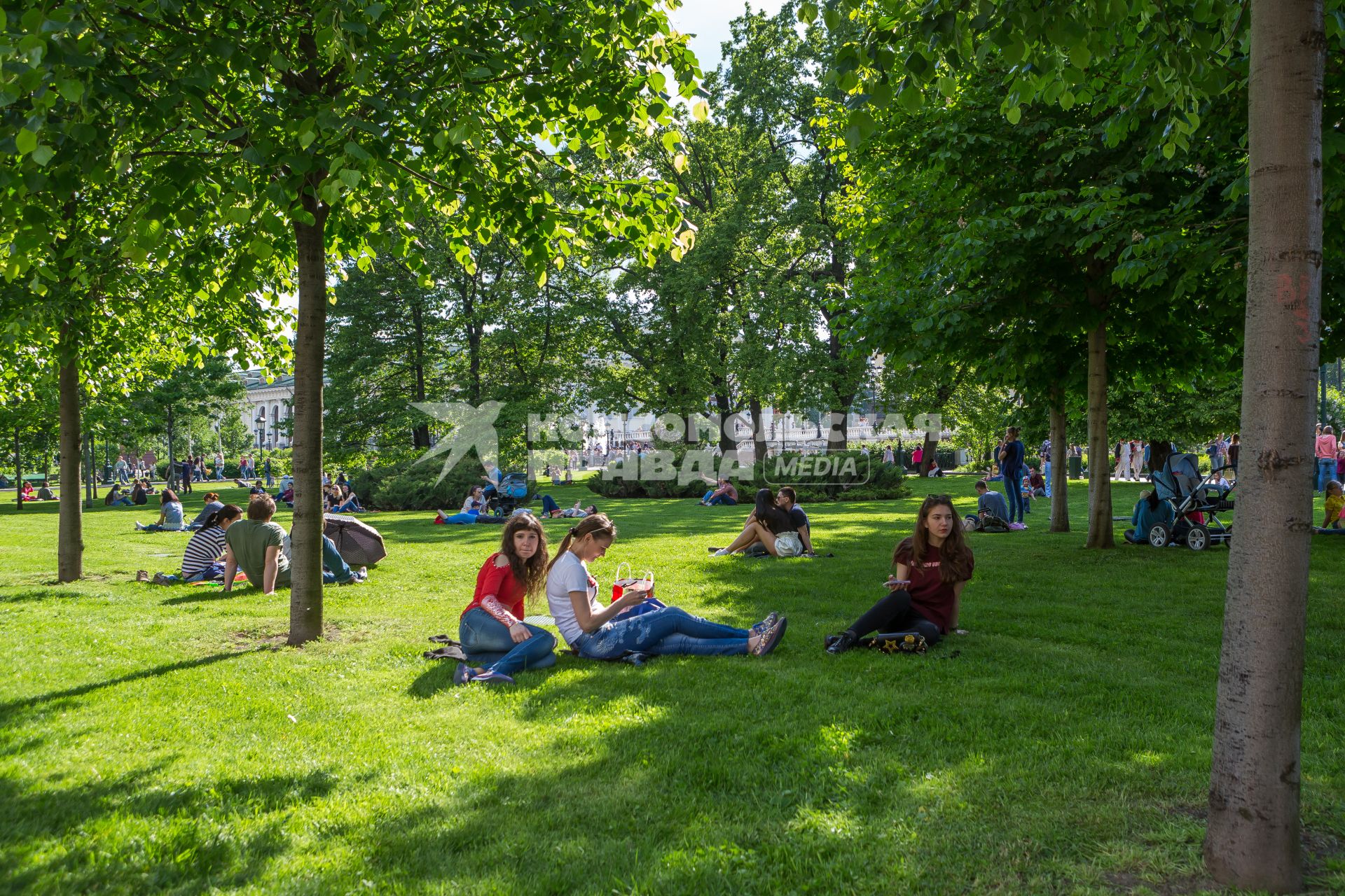 Москва.  Молодые люди отдыхают на газоне в Александровском саду.