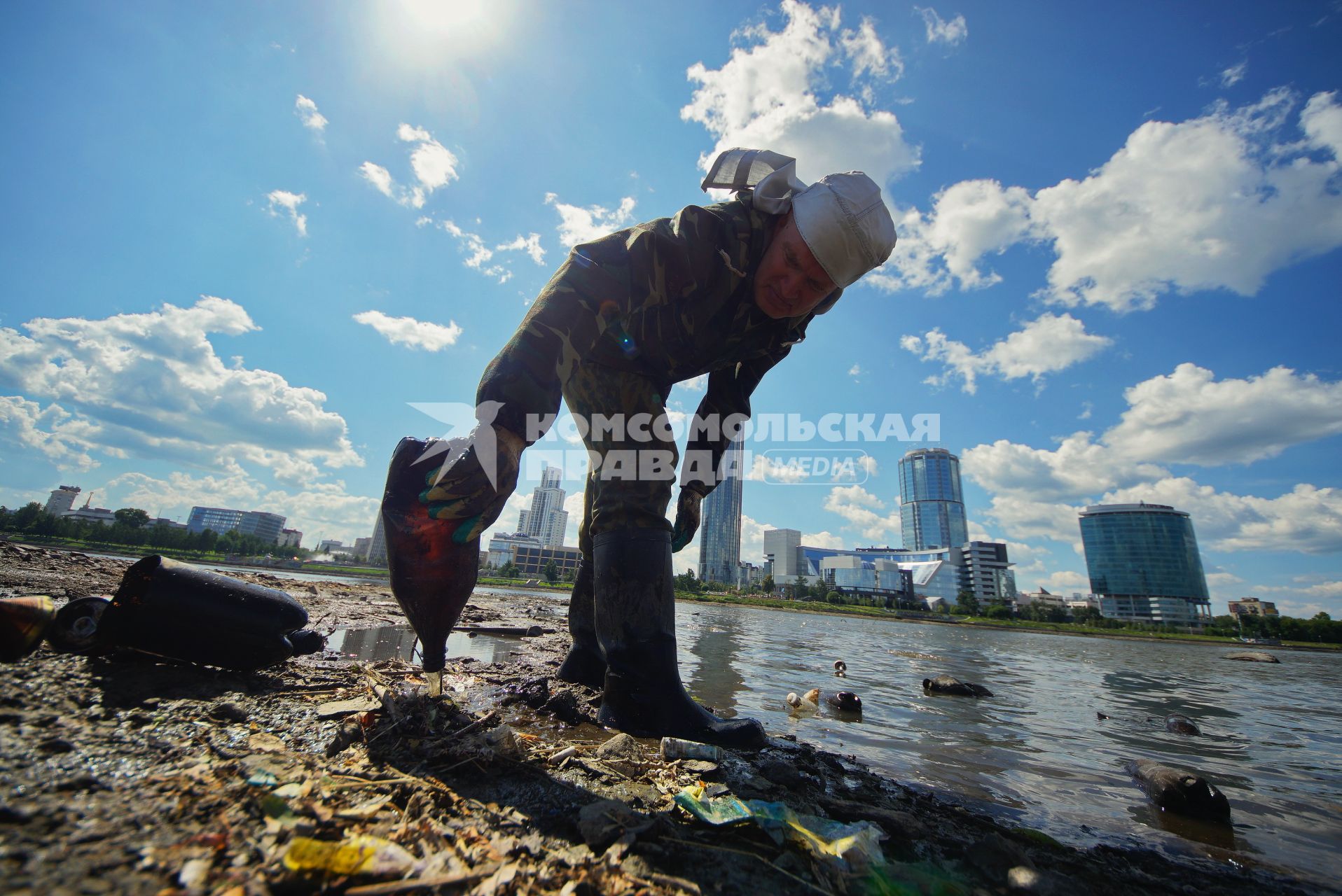 Екатеринбург. Волонтер собирает мусор с дна городского пруда обмелевших из-за сброса воды