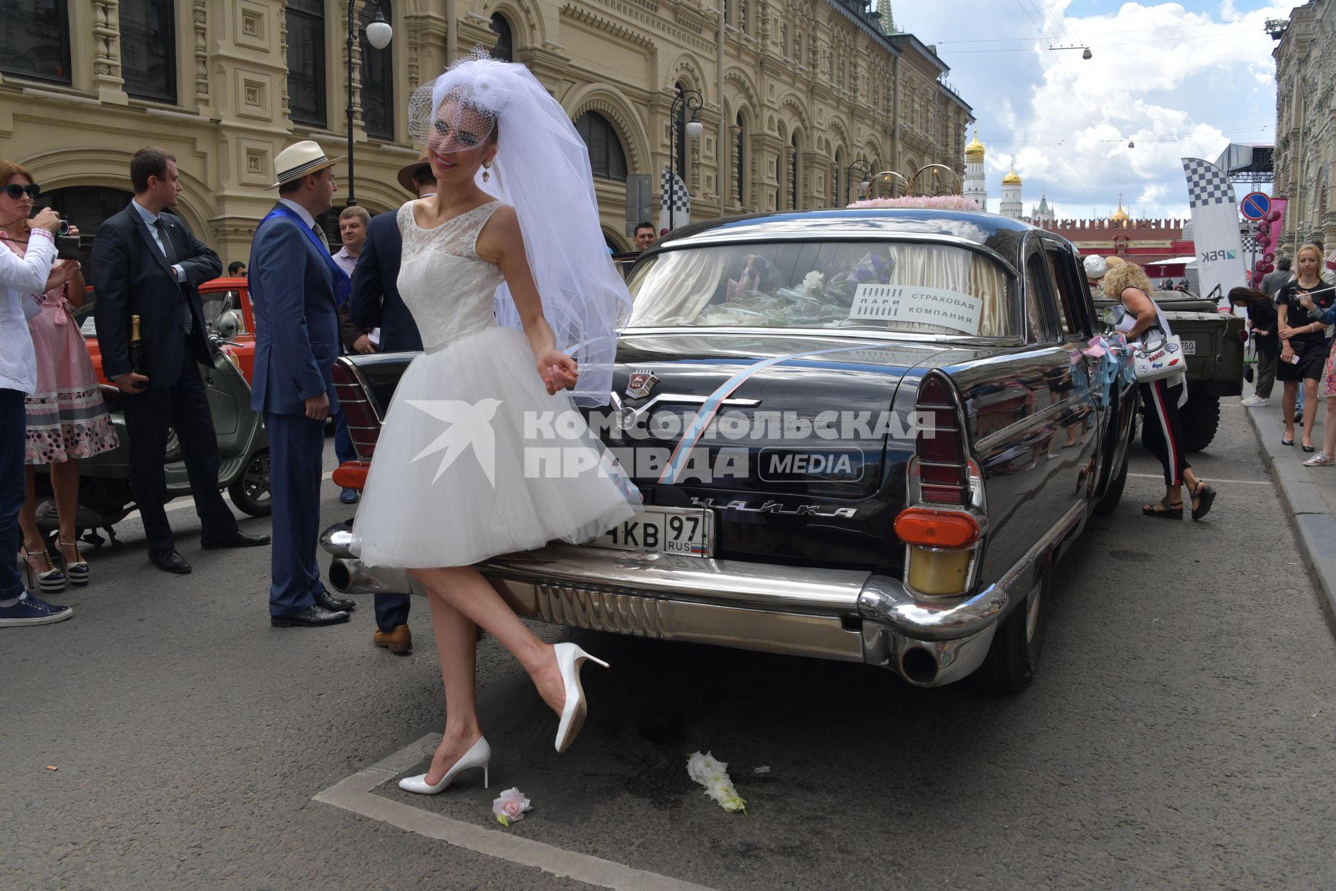 Москва.  Девушка в платье невесты рядом с автомобилем`Чайка`перед  стартом  ГУМ-авторалли Gorkyclassic-2017 возле ГУМа.