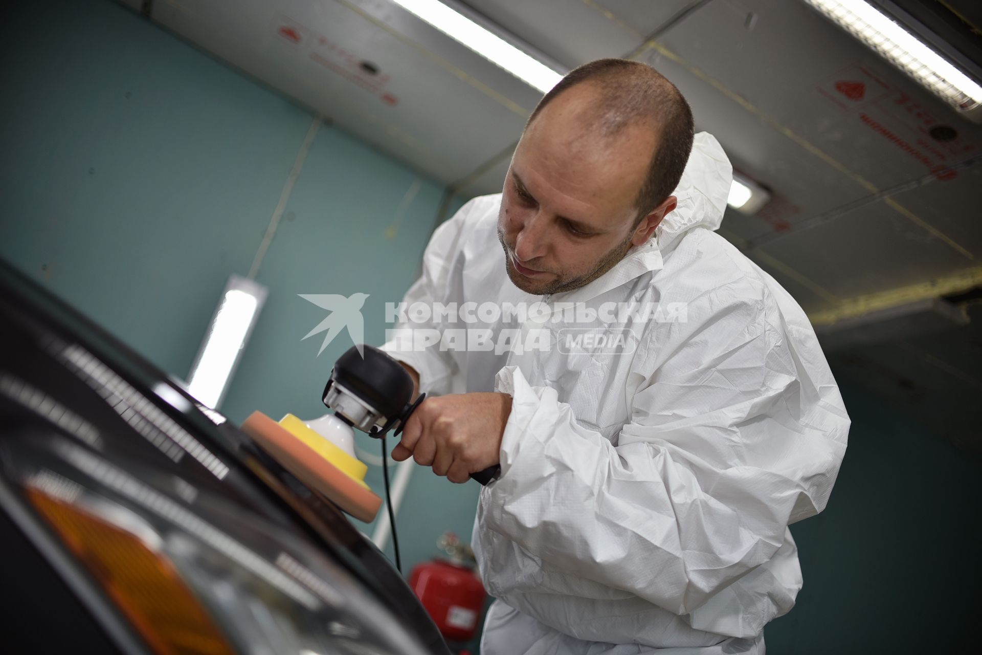 Новосибирск.  Сотрудник автосервиса полирует кузов автомобиля.