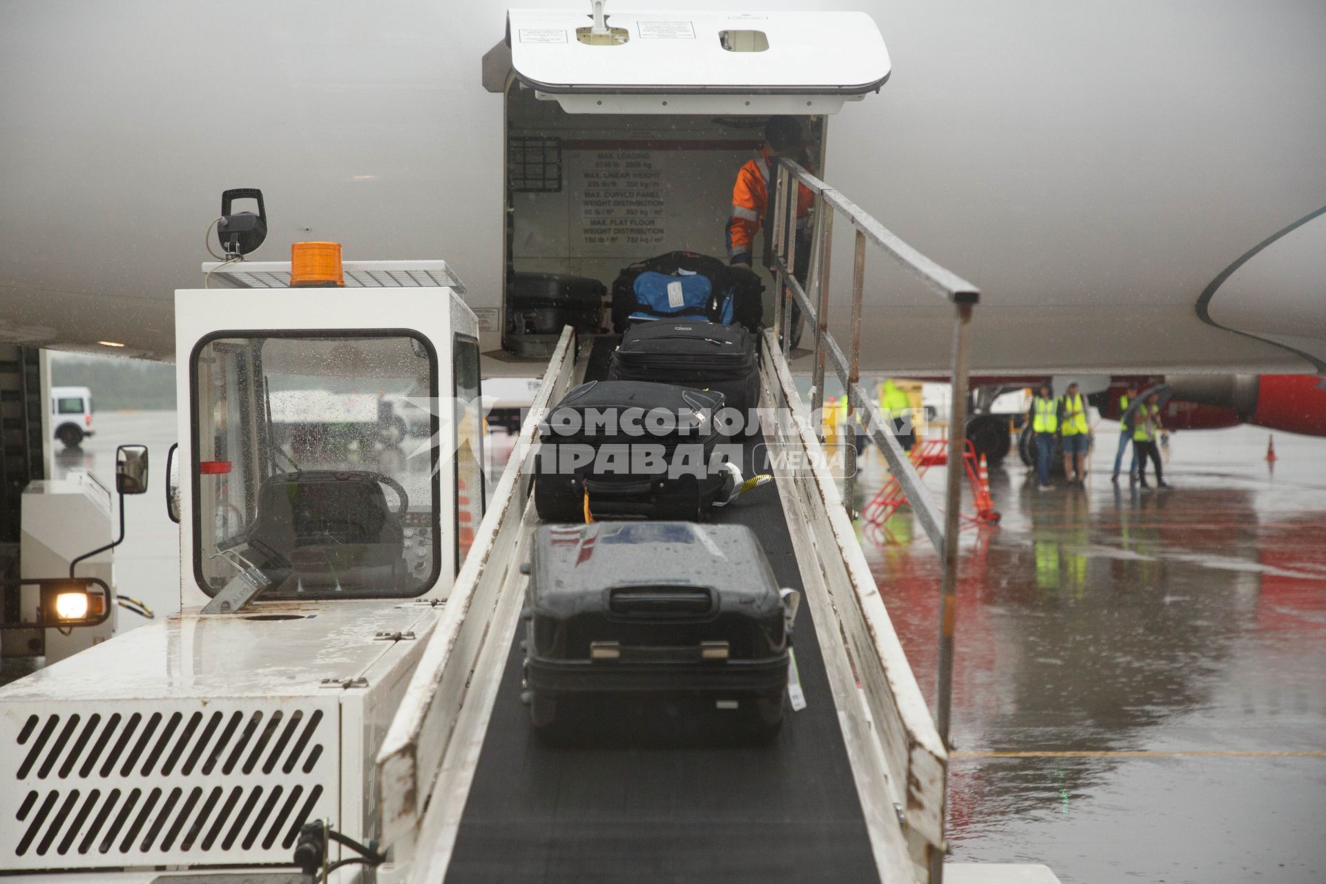 Санкт-Петербург. Загрузка багажа пассажиров в самолет  Bombardier CS300 авиакомпании airBaltic в аэропорту `Пулково`.