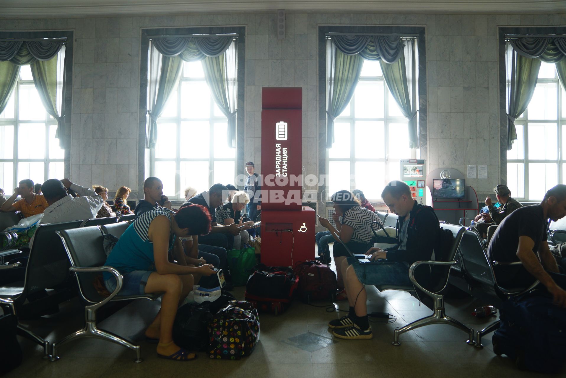 Екатеринбург. Пассажиры железнодорожного вокзала в зале ожидания у зарядной станции.