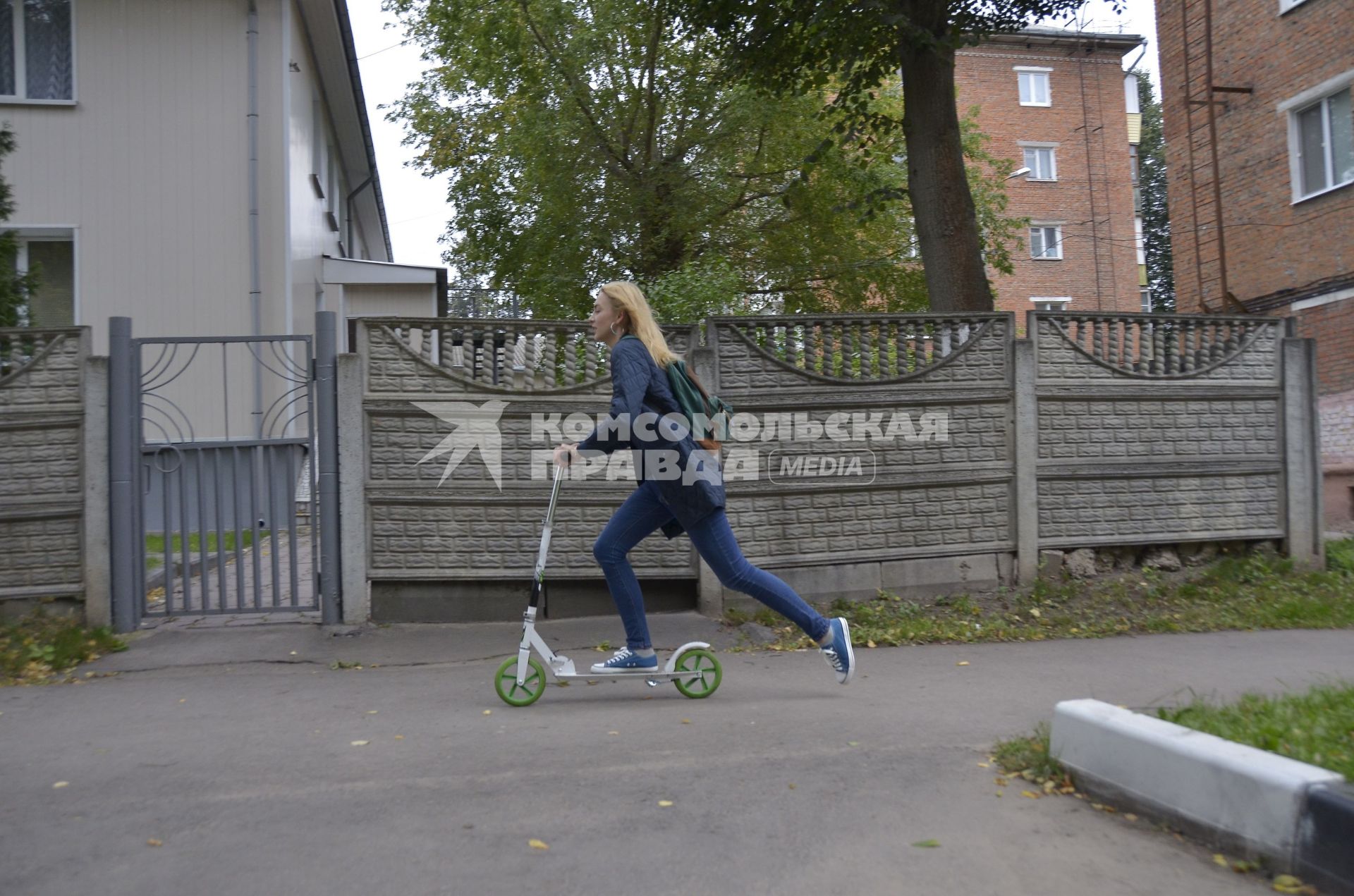 Тула. Девушка на самокате едет по городу.