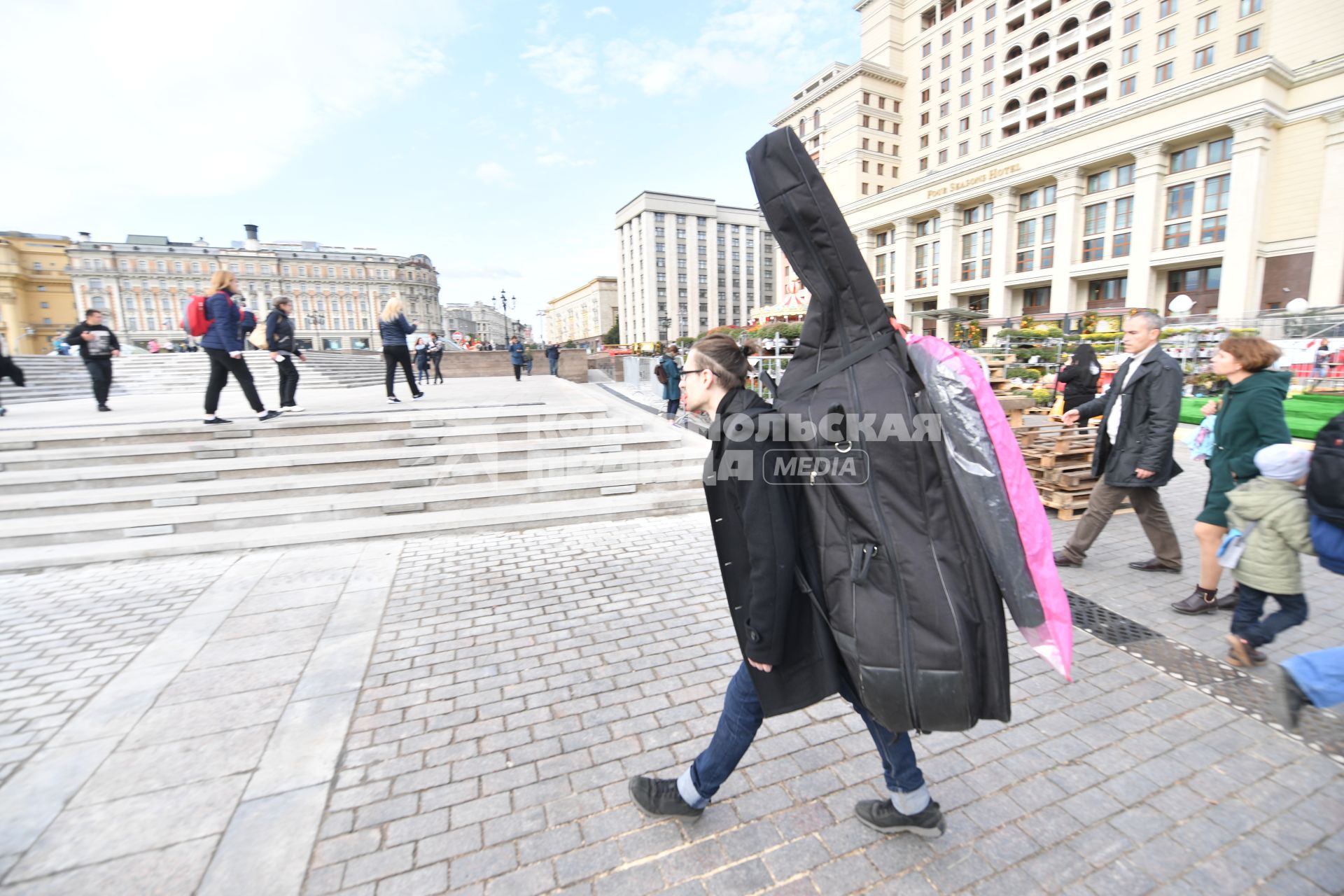 Москва. Мужчина с контрабасом идет по Манежной площади.