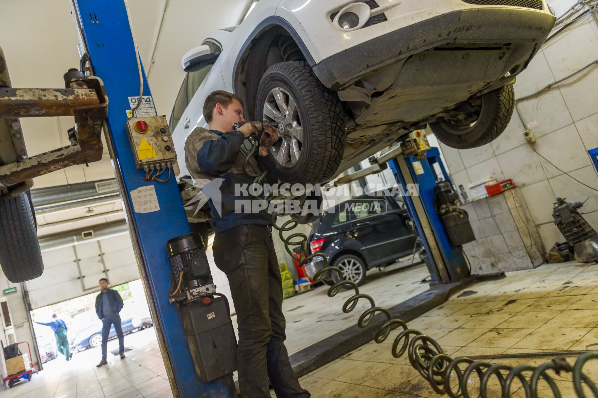 Санкт-Петербург. Автомеханник   производит ремонт колеса автомобиля в автосервисе.