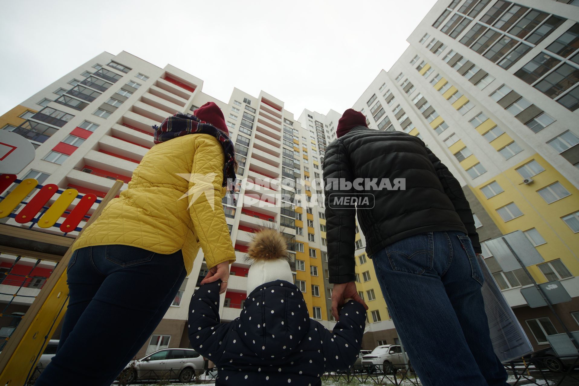 Екатеринбург.  Мужчина и женщина с ребенком смотрят на новостройку.