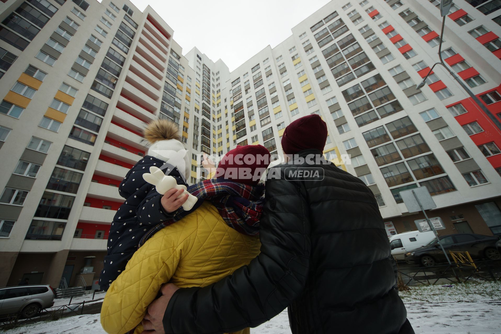 Екатеринбург.  Мужчина и женщина с ребенком смотрят на новостройку.