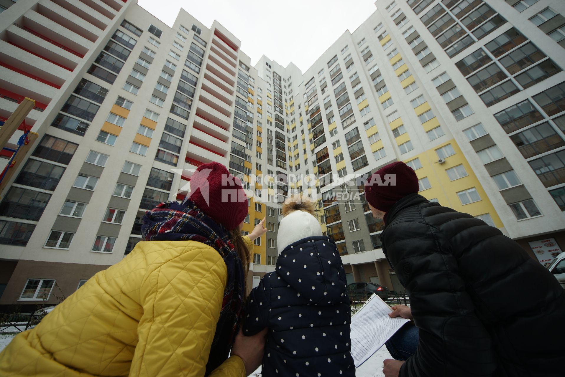 Екатеринбург.  Мужчина и женщина с ребенком смотрят на новостройку.