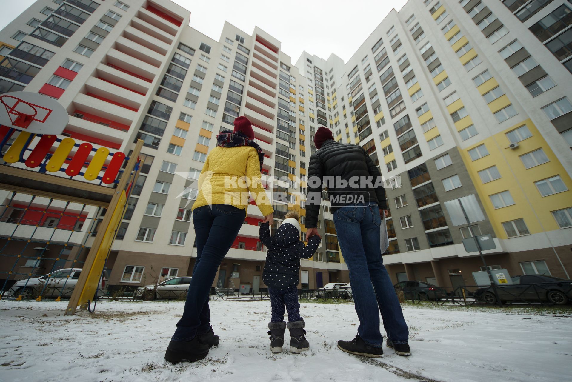 Екатеринбург.  Мужчина и женщина с ребенком смотрят на новостройку.